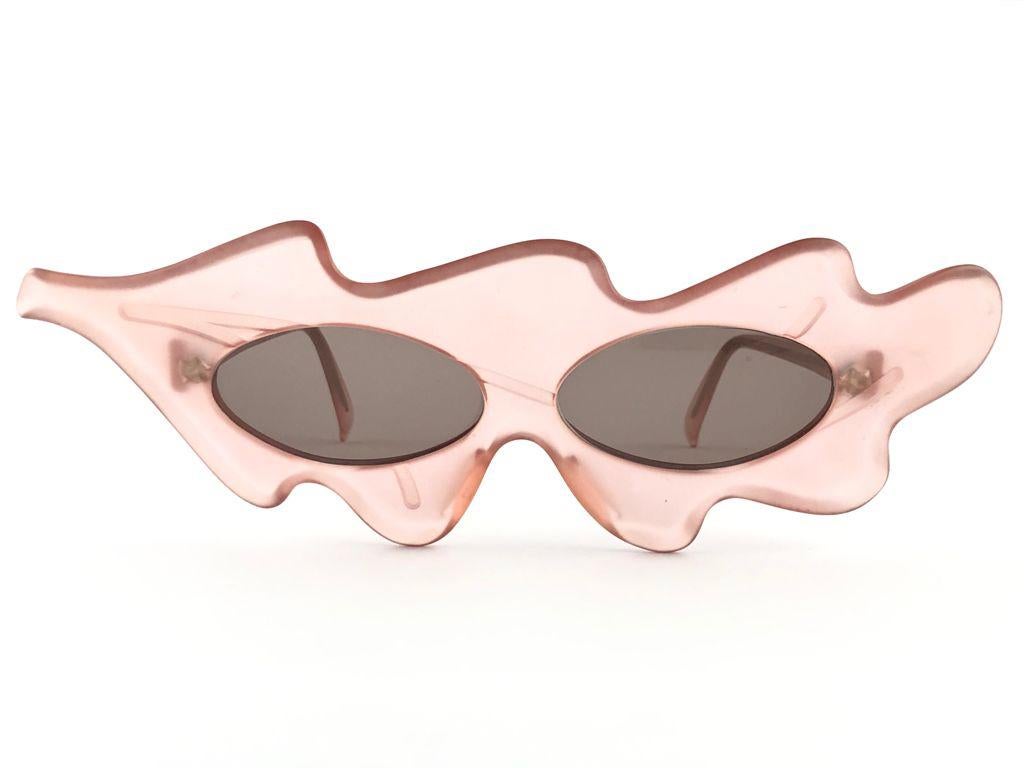 New Vintage Alain Mikli ultra wide translucent light rose frame.

Rare item in new and unworn condition. Spotless grey lenses.

Please consider that this item is nearly 40 years old so it could show minor sign of wear due to storage.

Made in