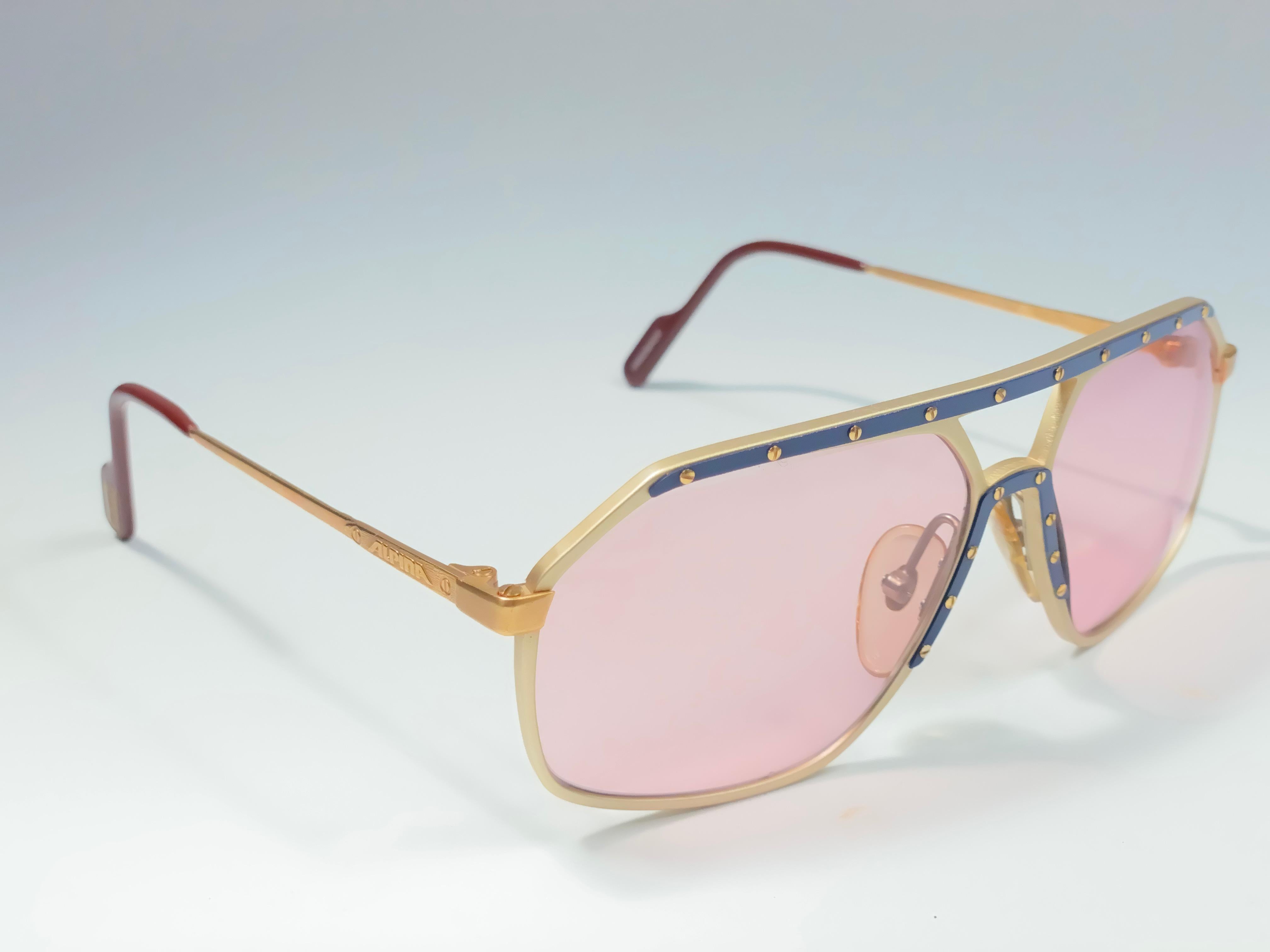 New Vintage Alpina M6 Aviator Sunglasses. Gold frame with blue accents and screws sporting candy pink lenses.
This pair has a minor sign of wear due to storage.
Handmade in West Germany.