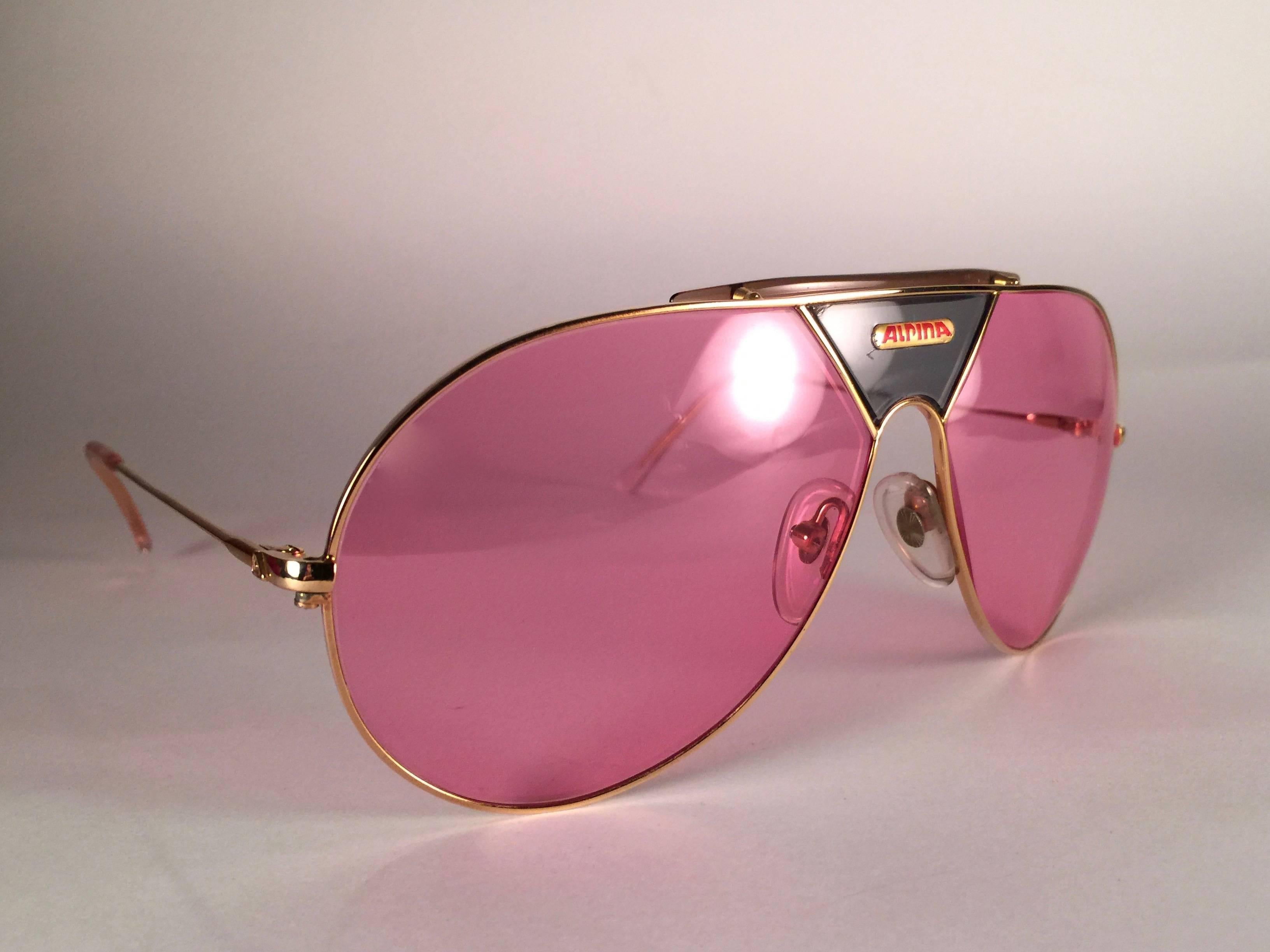 New Vintage Alpina TR4 Aviator Sunglasses. Gold frame with green insert and candy pink lenses.
This pair has a minor flaw near the Alpina logo area.
The very same model worn by Don Johnson in Miami Vice in the 1980's.
Made in West Germany.