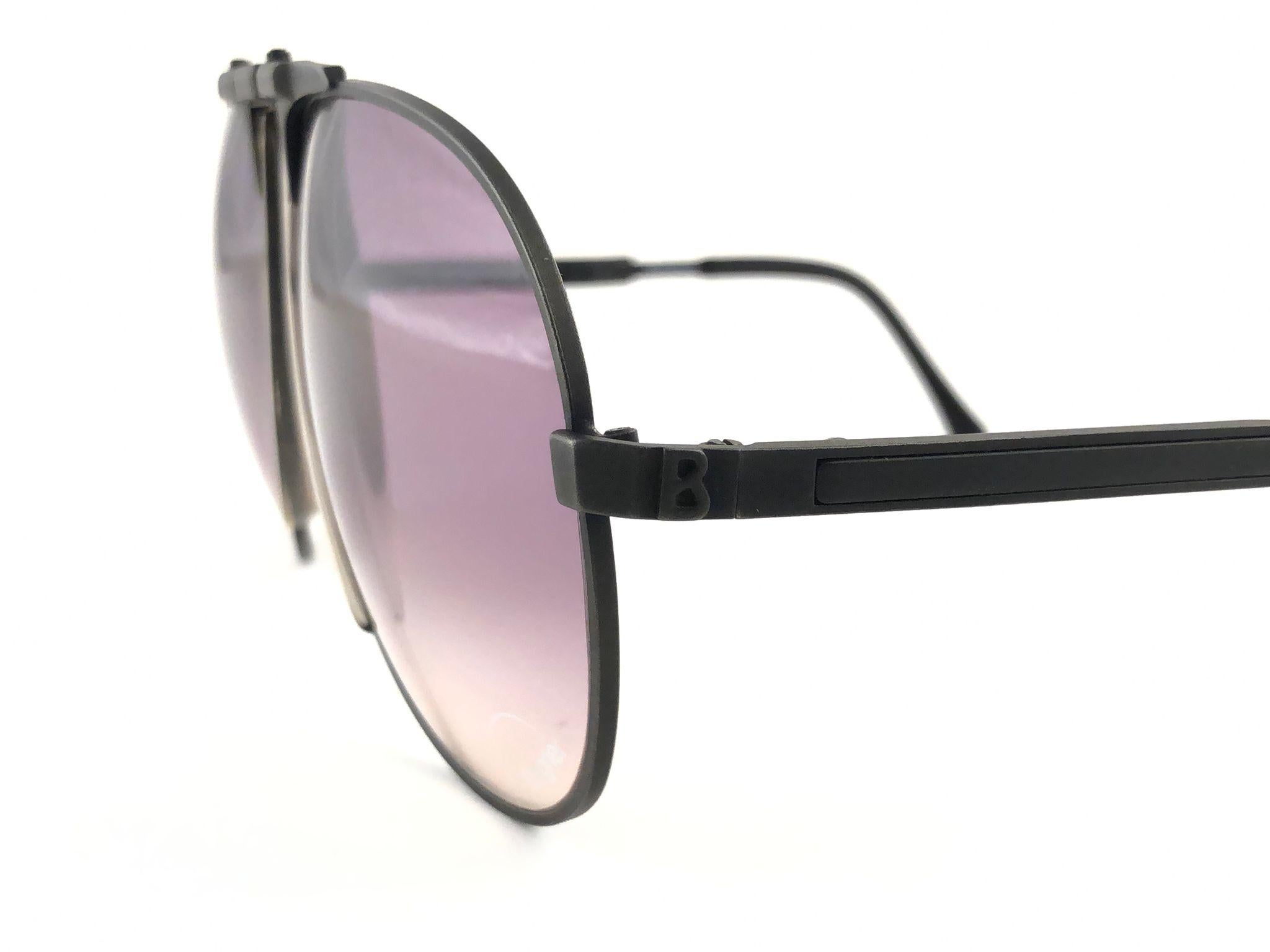 Collector's item. 
New vintage Bogner by Eschenbach sunglasses 70011 Medium size in matte black with purple gradient lenses. 
The model is from the same series ( 7000's ) used by the late Roger Moore in 007's 