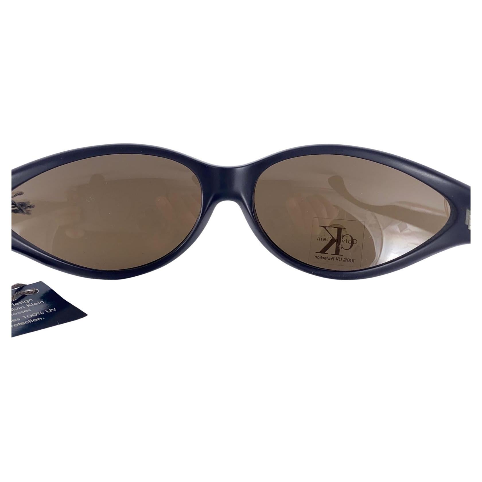 












New Vintage Calvin Klein Y2K 1990'S Wrap Around Brown Frame Sunglasses Made In Italy
Blue Lenses.

New, Never Worn Or Displayed.

This Item May Show Minor Sign Of Wear Due To Storage.

Front : 18 Cms
Lens Height : 3.8  Cms
Lens Width :