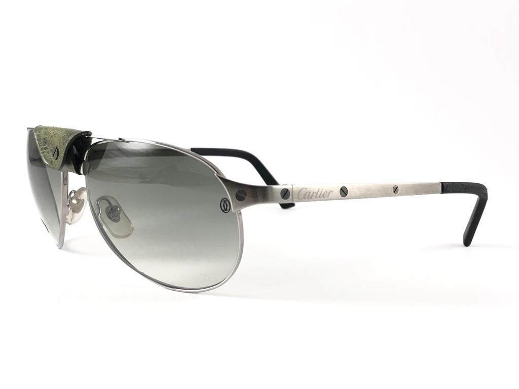 New 1990 Cartier Edition Santos Dumont Sunglasses with medium grey gradient original Cartier (uv protection) lenses. All hallmarks.  Removable green leather piece.
These are like a pair of jewels on your nose. 
Please notice that this sunglasses are