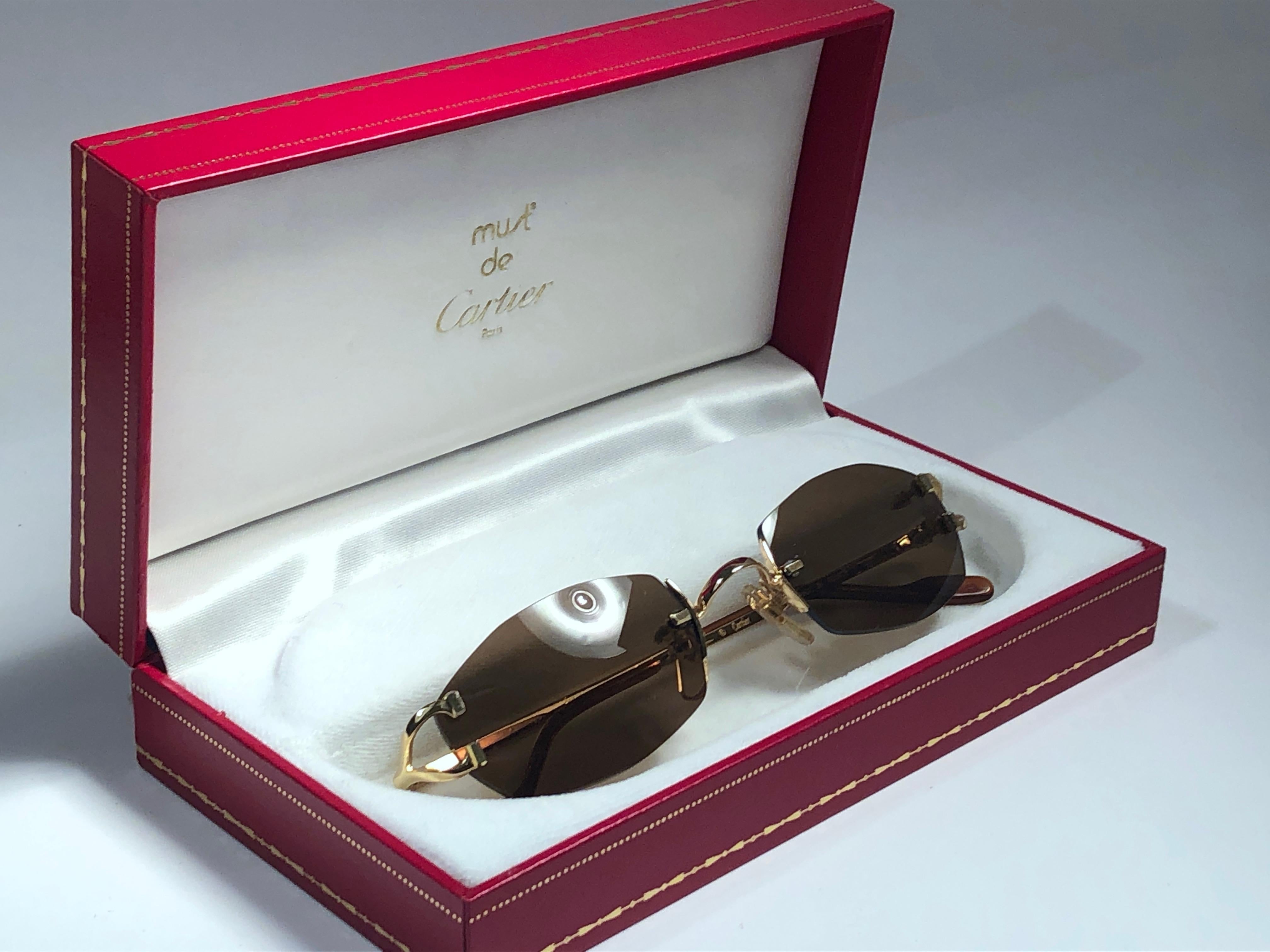 New 1990 Cartier Capri unique rimless sunglasses with solid brown  (uv protection) lenses. Frame with the front and sides in gold.  All hallmarks. Cartier gold signs on the honey brown ear paddles. These are like a pair of jewels on your nose.