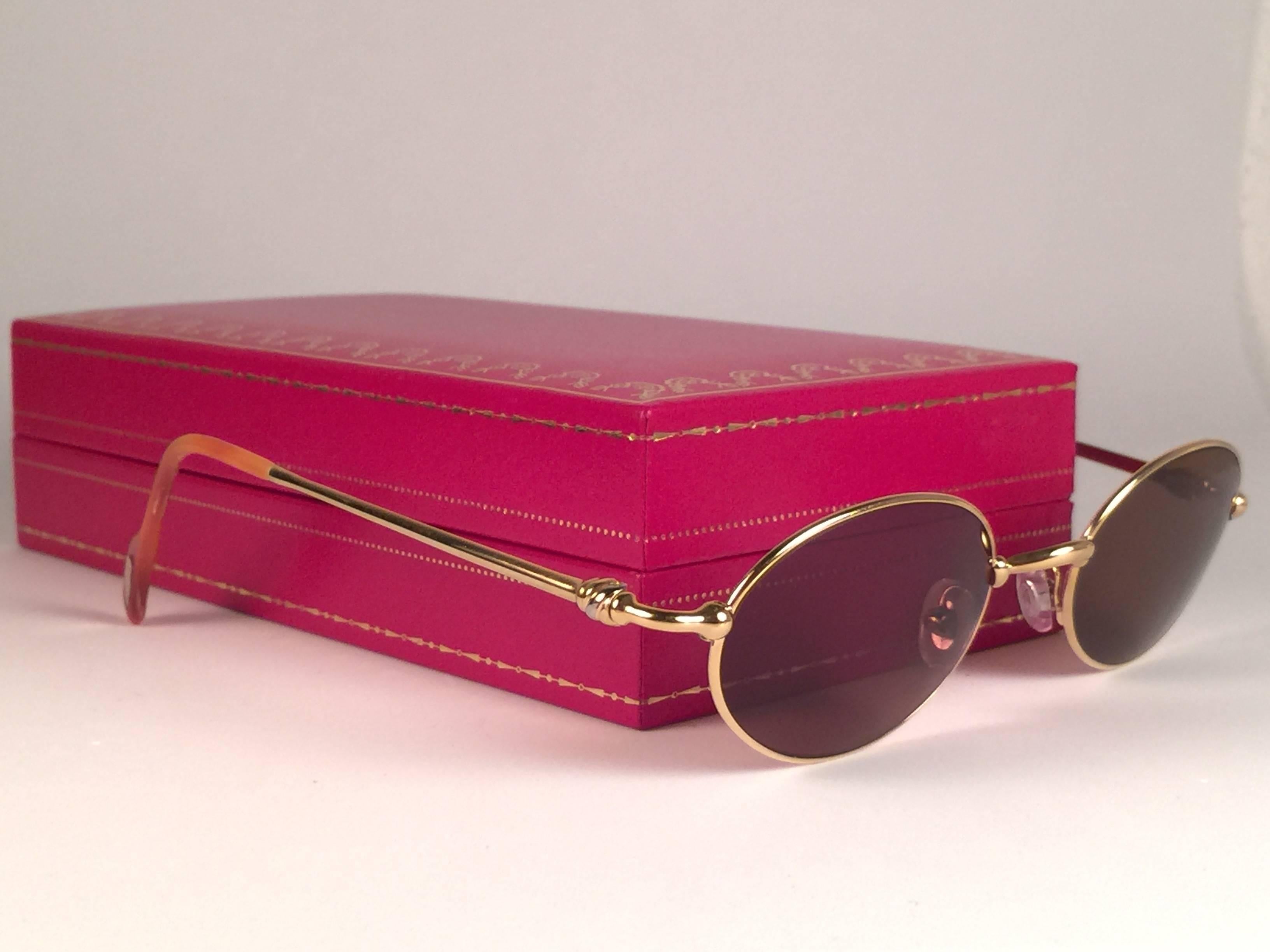 New 1990 Cartier Filao Sonnenbrille mit massiven braunen (UV-Schutz) Gläsern.  Alle Markenzeichen.  Cartier-Goldzeichen auf den Ohrmuscheln.  
Sie sind wie ein Paar Juwelen auf der Nase. Bitte beachten Sie, dass dieses Paar fast 30 Jahre alt ist und