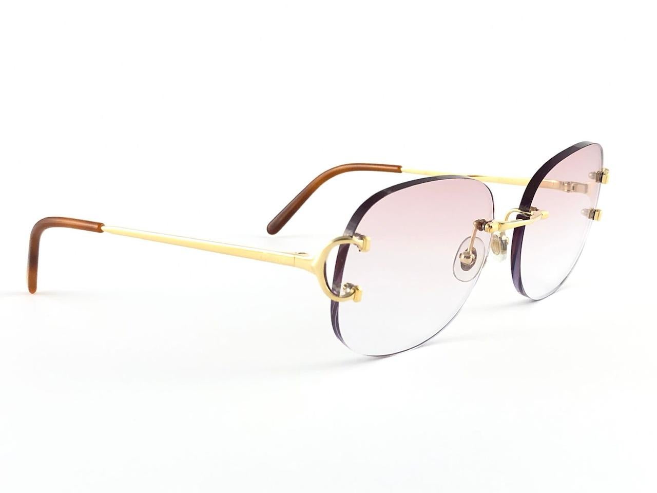 New 1990 Cartier gold plated unique rimless sunglasses with light rose gradient  (uv protection) lenses. Frame with the front and sides in gold. All hallmarks. 

Cartier signs on the black ear paddles. 

Please notice this item its nearly 30 years