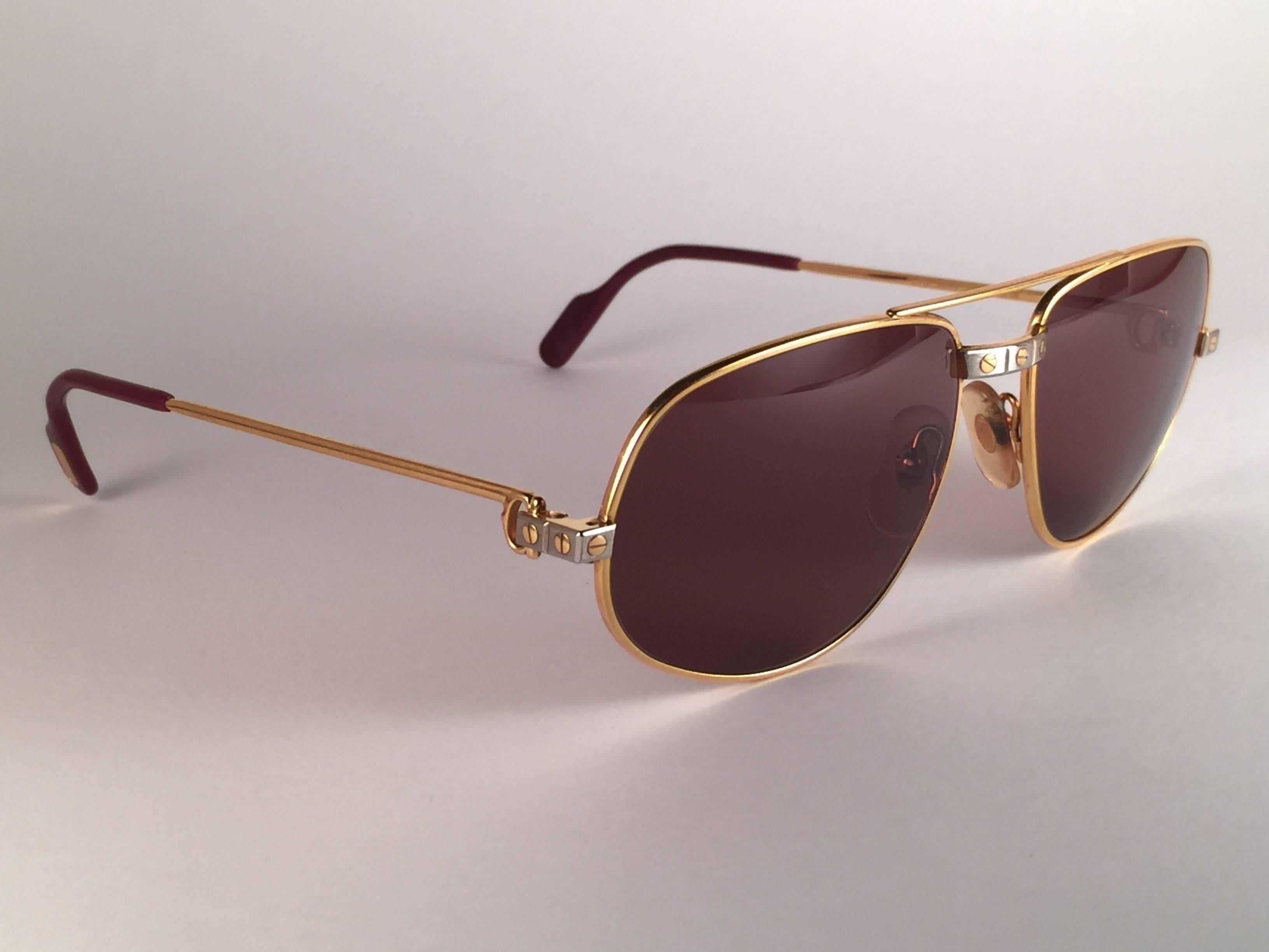 Lunettes de soleil vintage Cartier Romance Santos avec les verres marron miel (protection contre les UV).  Le cadre est avec le recto et les côtés en or jaune et blanc. Tous les poinçons. Émail rouge avec signes en or de Cartier sur les palettes