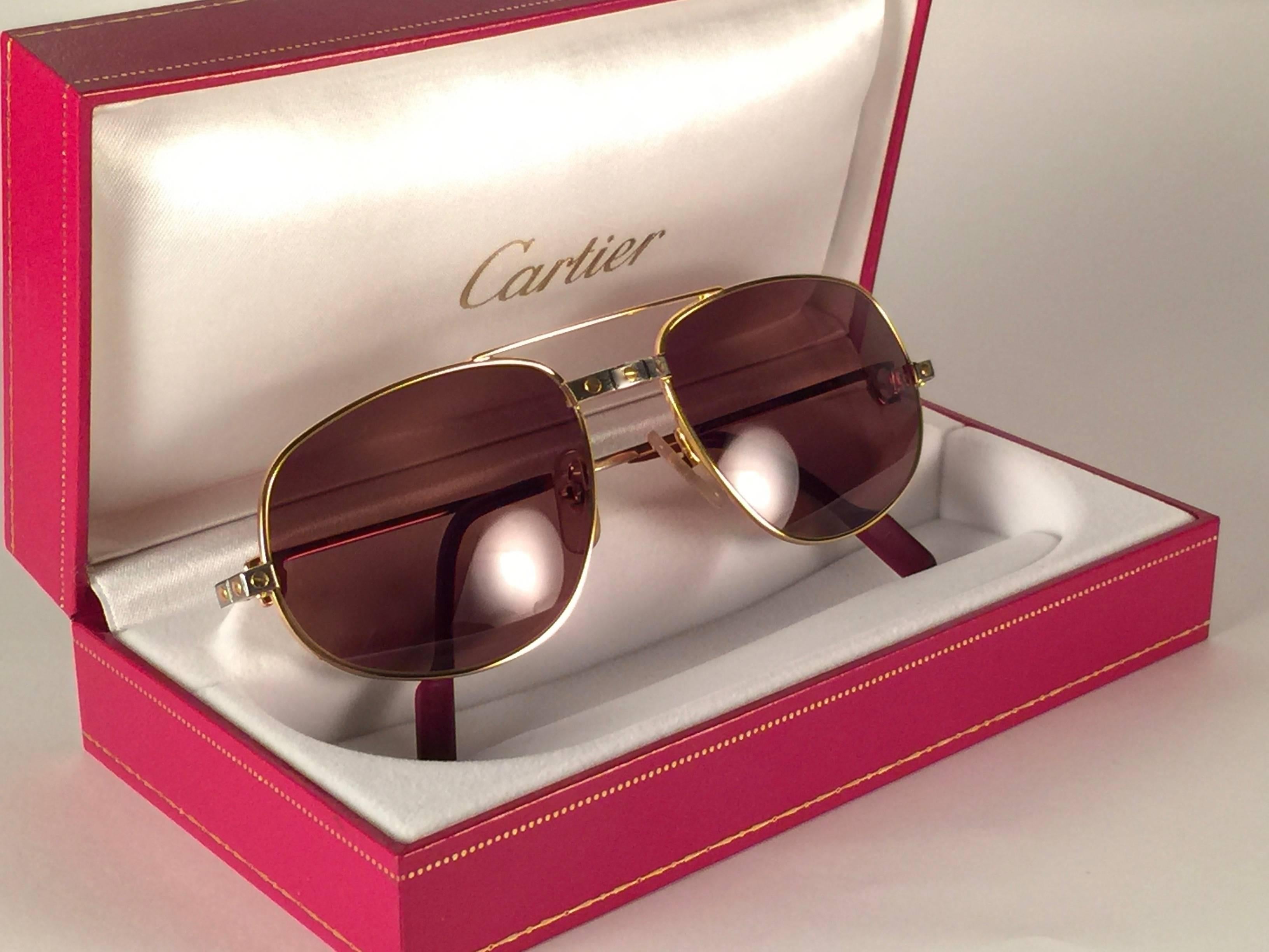 Vintage Cartier Romance Santos sunglasses with solid brown (uv protection)lenses.  
Frame is with the front and sides in yellow and white gold.  All hallmarks. 
Red enamel with Cartier gold signs on the ear paddles. 
Both arms sport the C from