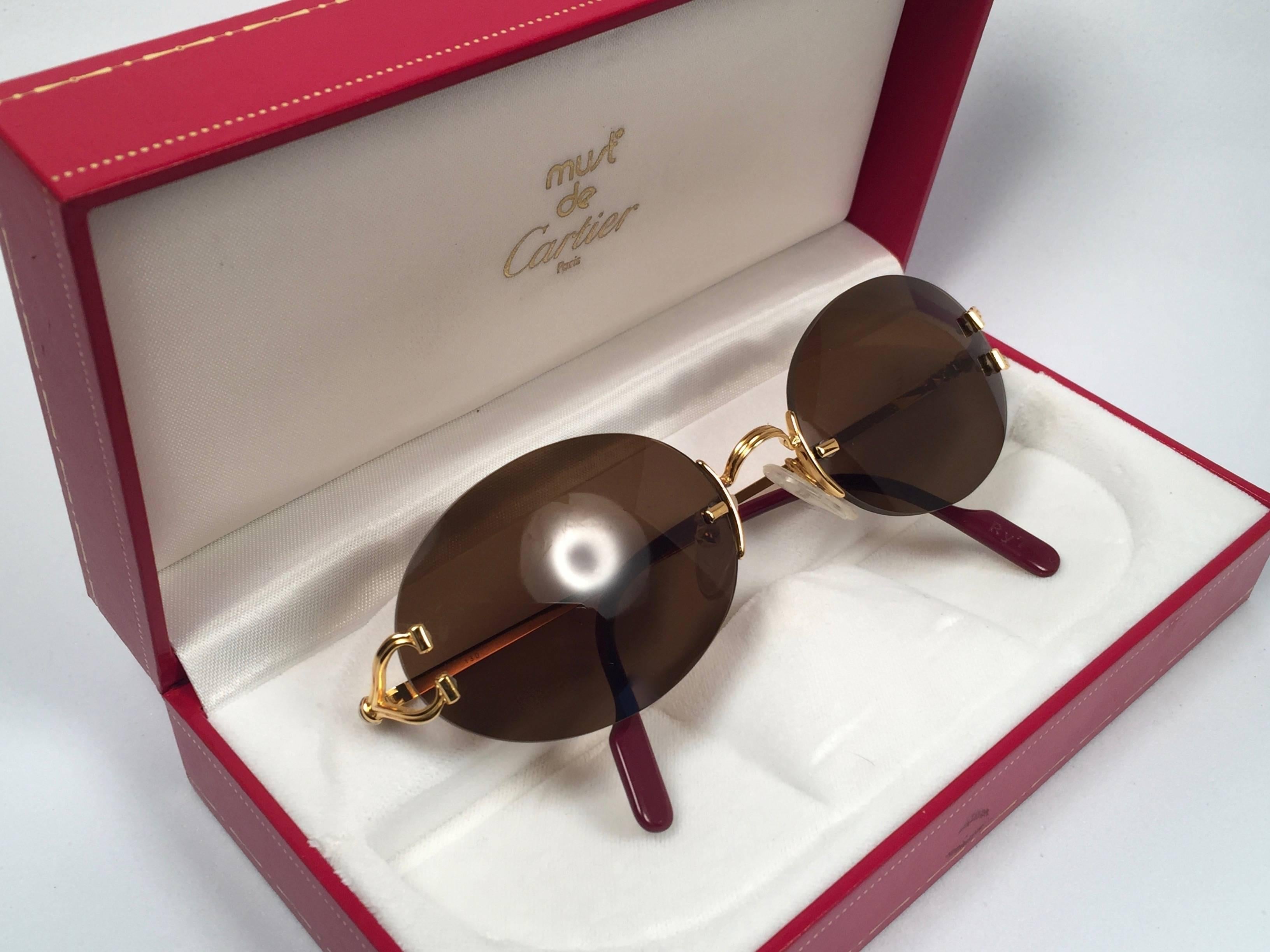 New 1990 Cartier Scala Special Edition with crevasse on the gold pieces. Unique rimless sunglasses with brown  (uv protection) lenses. Frame with the front and sides in gold. All hallmarks. Cartier gold signs on the honey ear paddles. These are like