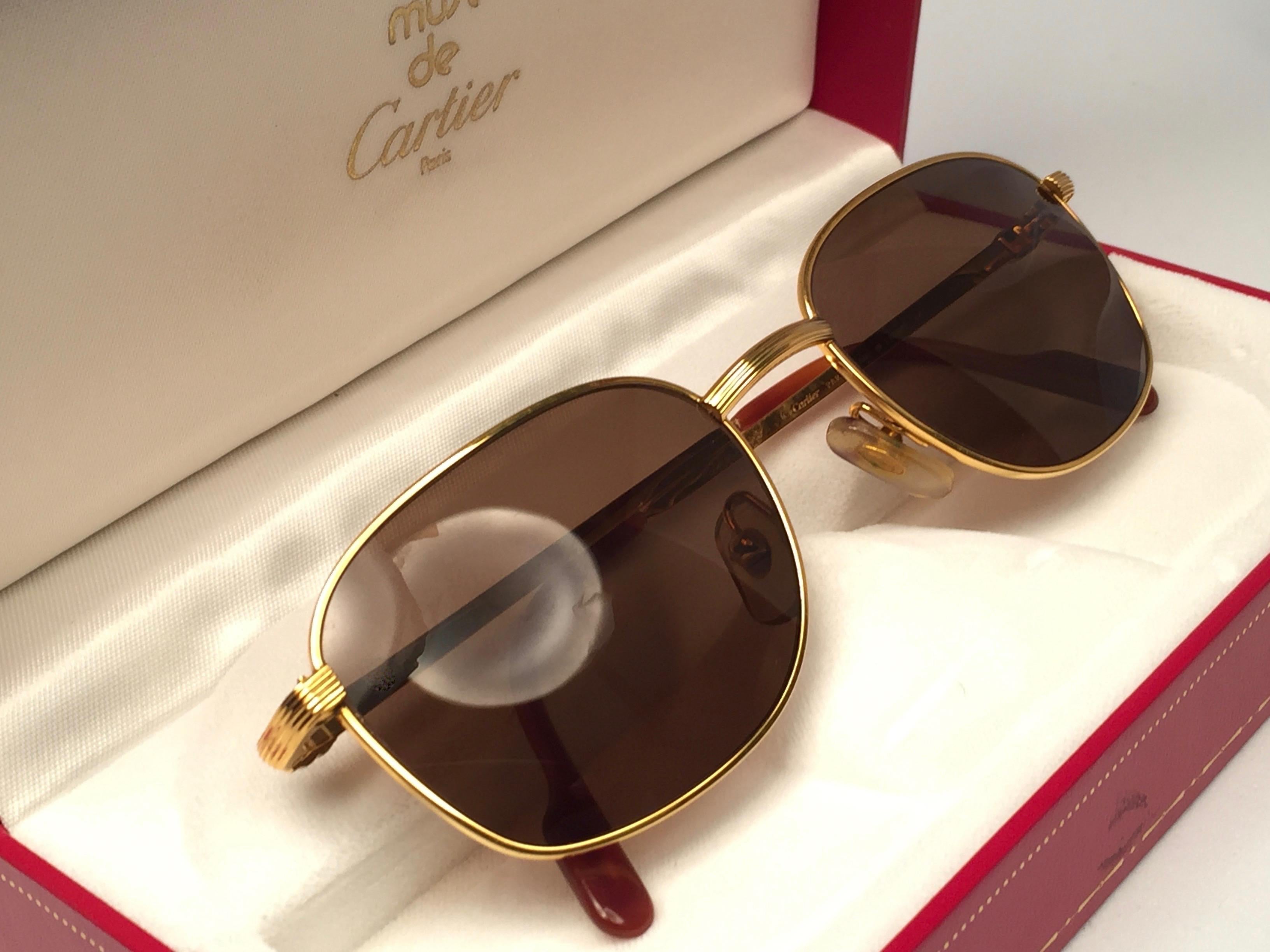 New 1990 Cartier Segur 54MM Sunglasses with brown (uv protection) lenses.  All hallmarks. Cartier gold signs on the ear paddles. These are like a pair of jewels on your nose. This piece may have minor sign of wear due to storage.
Beautiful design