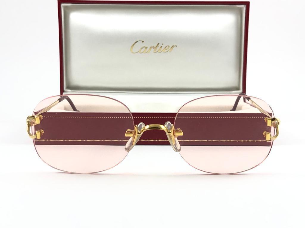 Neu 1990 Cartier vergoldete einzigartige randlose Sonnenbrille mit hellrosa Farbverlauf  (UV-Schutz) Linsen. Rahmen mit goldfarbener Front und Seiten. Alle Markenzeichen. 

Cartier-Zeichen auf den schwarzen Ohrmuscheln. 

Bitte beachten Sie, dass
