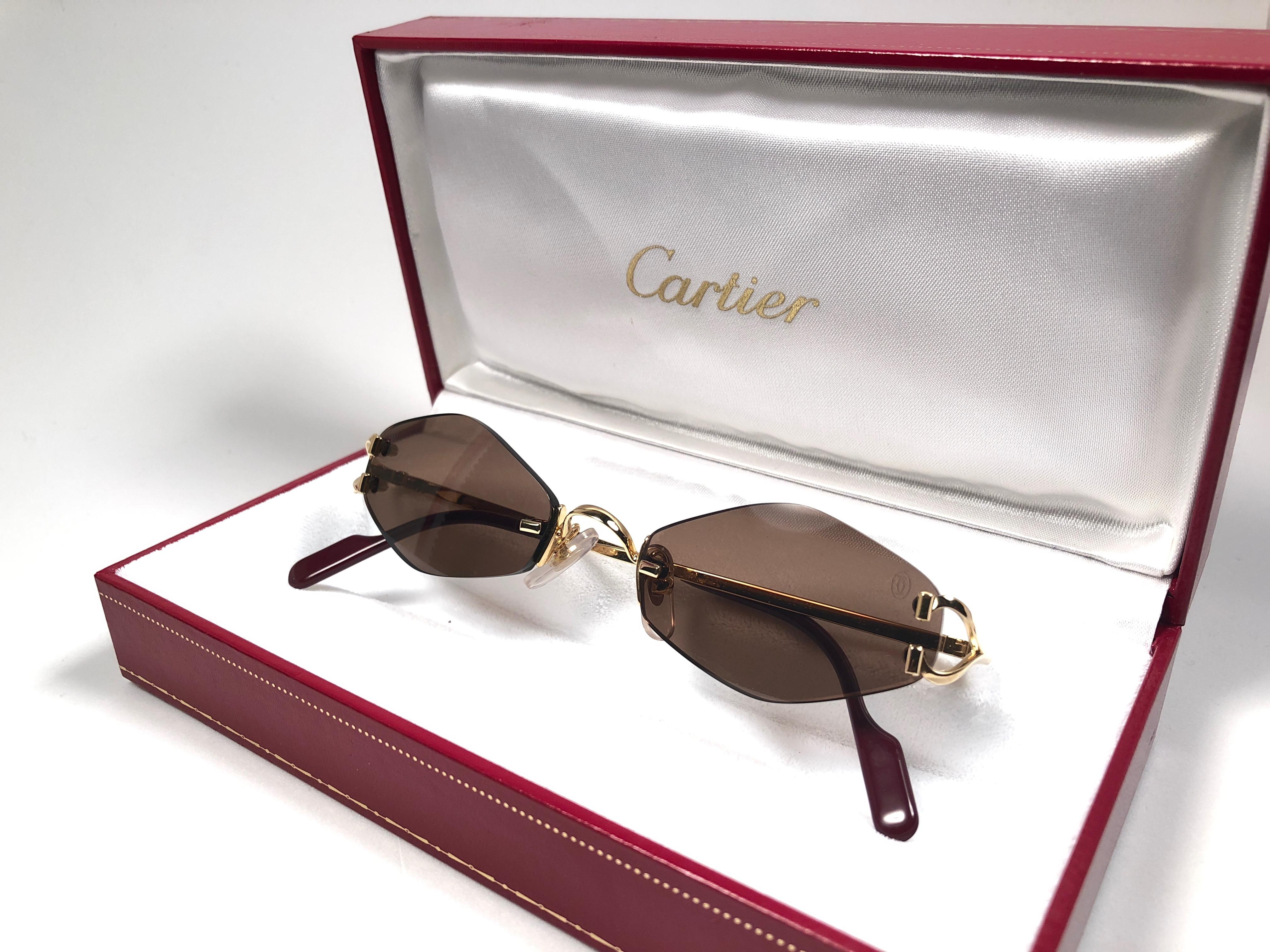 New 1990 Cartier Soho unique rimless sunglasses with brown original Cartier  (uv protection) lenses. Frame with the front and sides in gold.  All hallmarks. Cartier gold signs on the honey brown ear paddles. These are like a pair of jewels on your