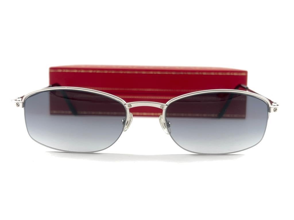 New 1990 Cartier Titanium halb randlose Sonnenbrille mit grauen (uv-Schutz) Gläsern.  Alle Markenzeichen. 

Cartier-Zeichen auf den schwarzen Ohrmuscheln. 

Bitte beachten Sie, dass dieser Artikel fast 30 Jahre alt ist und aufgrund der Lagerung