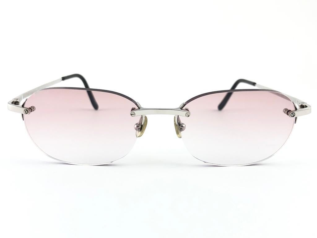 New 1990 Cartier Titanium unique rimless sunglasses with light rose gradient  (uv protection) lenses. Frame with the front and sides in titanium. All hallmarks. 

Cartier signs on the black ear paddles. 

Please notice this item its nearly 30 years
