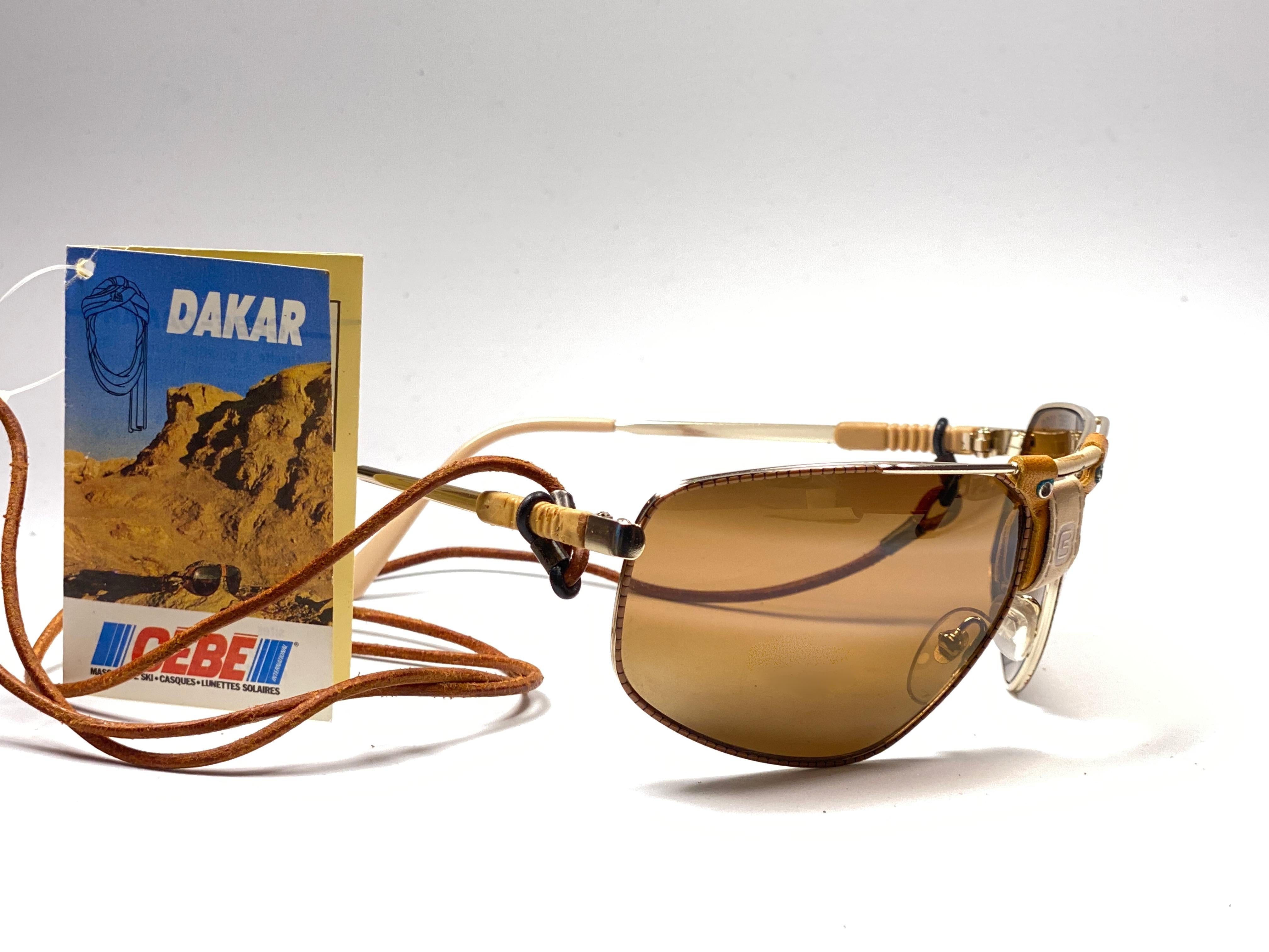 New Vintage Cebe Dakar gold awith leather accents on nose bridge and removable cord sunglasses. From the very same series as the ones worn by the great Miles Davis.

Sturdy and cool frame sporting a pair of double gradient gold lenses. 

Never worn