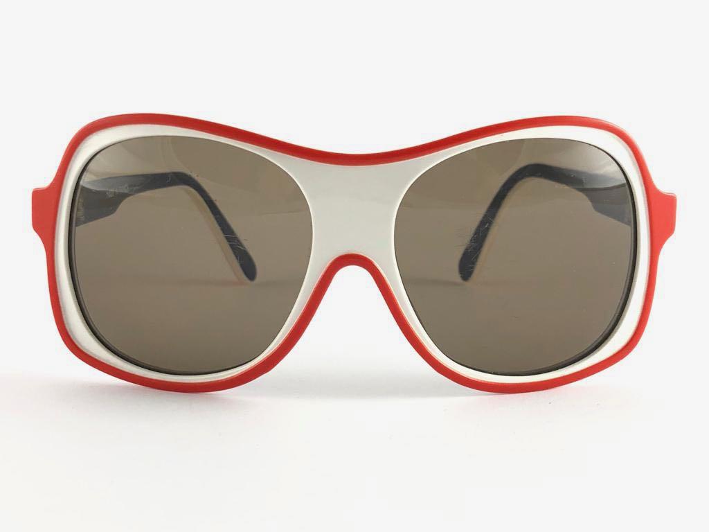 Oversized white, red and blue ultra light frame with medium brown lenses.
Never worn or displayed. This item may show minor sign of wear due to storage.

Front                       13.5 Cms
Lens Height               5    Cms
Lens Width             