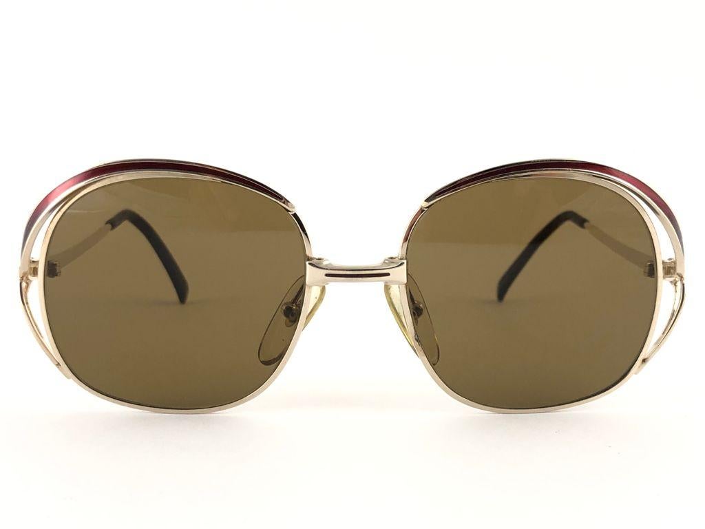 New vintage Christian Dior gold with burgundy details frame.

Solid brown lenses.

This item may show light sign of wear due to storage.

Made in Austria

MEASUREMENTS:

FRONT : 13 CMS
LENS HEIGHT : 4.6 CMS
LENS WIDTH : 4.8 CMS
TEMPLES : 11.5 CMS