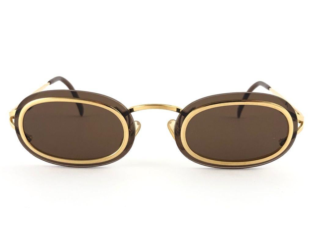 New Vintage Christian Dior 2970 small gold oval frame sporting solid brown lenses. 

Made in Germany.
 
Produced and design in 1980's.

New, never worn or displayed. This piece could show minor sign of wear due to storage.

MEASUREMENTS:

FRONT : 13