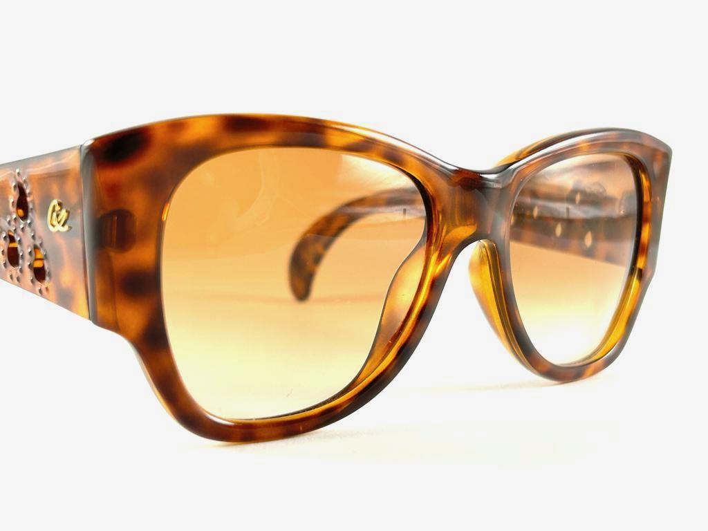 Rare pair of New vintage Christian Lacroix sunglasses. 

Translucent tortoise with elaborated gold accents, cat eyed shaped frame holding a pair of spotless  lenses.

New, never worn or displayed. Made in France.


FRONT : 15 CMS

LENS HEIGHT : 4.8