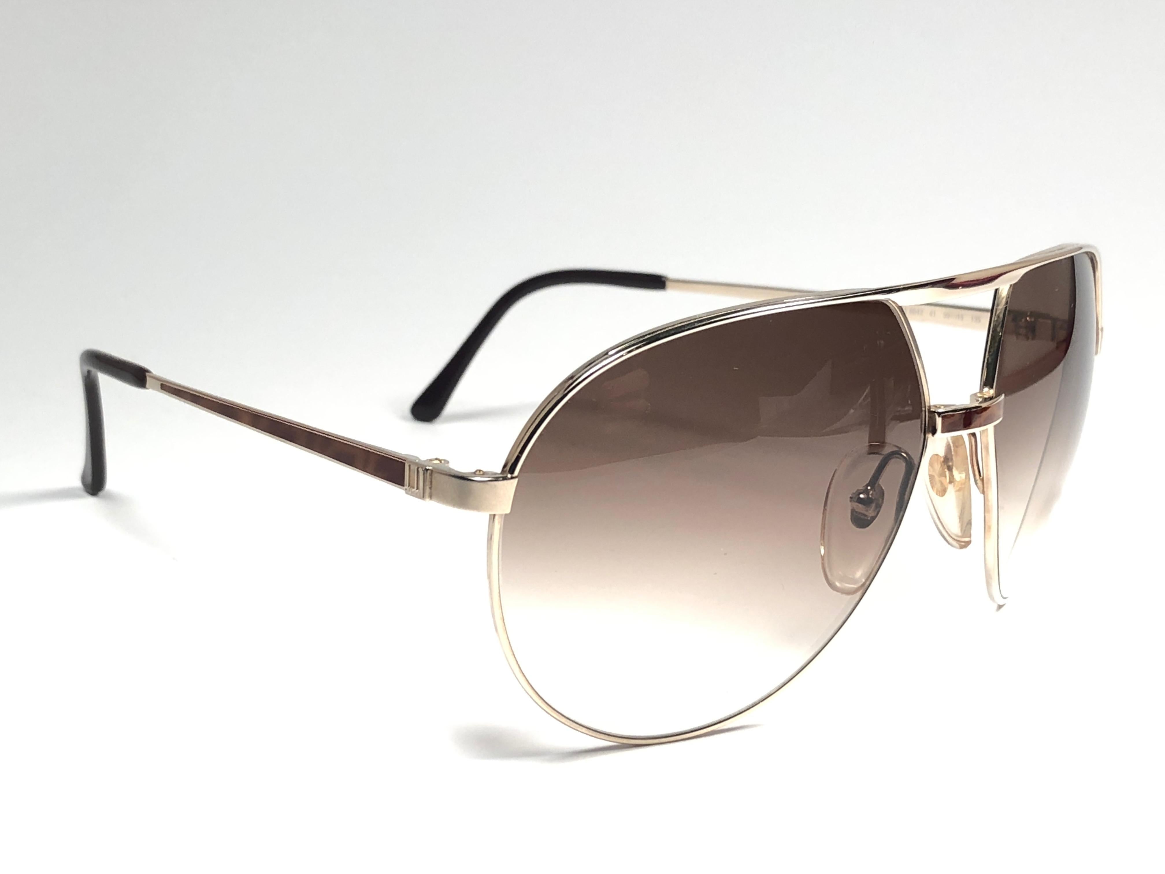 
New 1980 Dunhill gold with lace details on the nose bridge and temples sunglasses with brown gradient (uv protection) lenses. 
These are like a pair of jewels on your nose.
Beautiful design and a real sign of the times. 
Original Dunhill case.
This