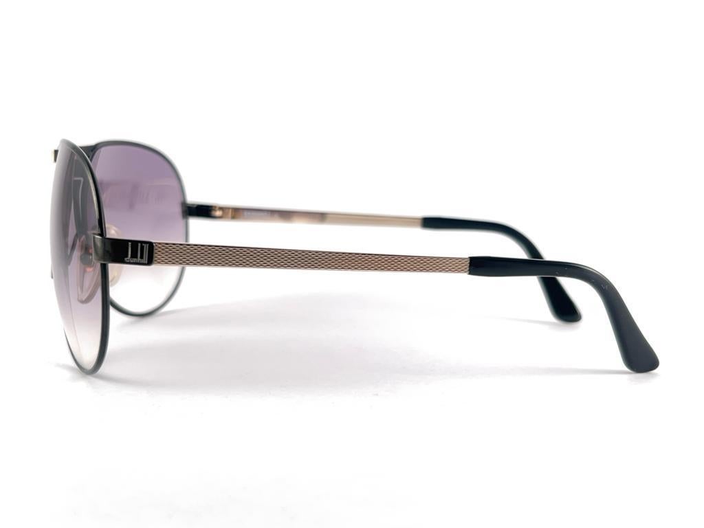
Neu 1980 Dunhill 6083 94 Sonnenbrille in Schwarz & Gold Details auf der Nase Brücke und Bügel. Lila Gradient Linsen. 
Sie sind wie ein Paar Juwelen auf der Nase.
Schönes Design und ein echtes Zeichen der Zeit. 
Dieses Stück kann geringfügige