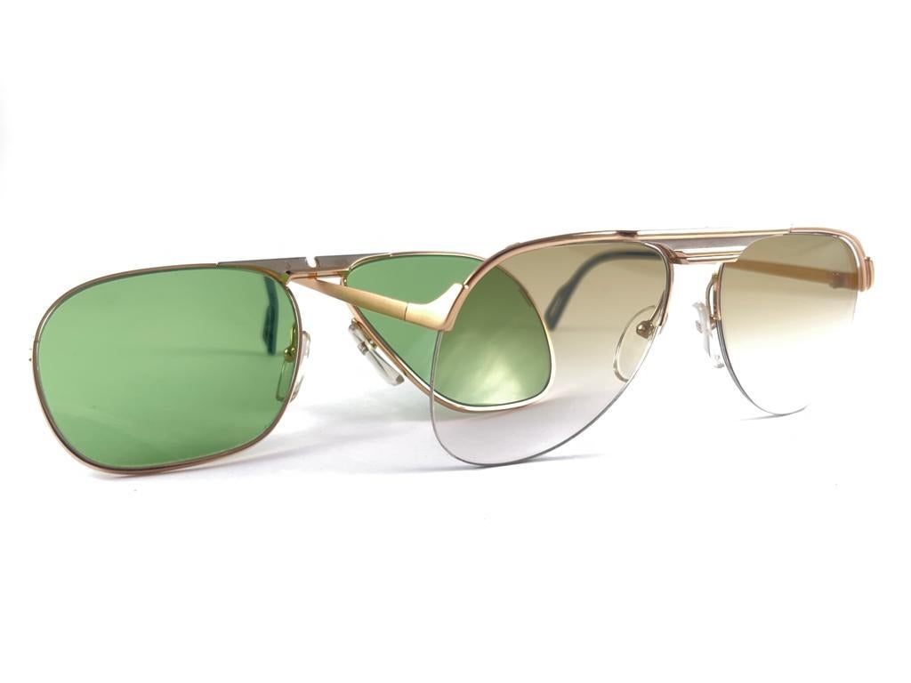 New Vintage Essilor White And Gold Accents Sunglasses. 

Cadre robuste et cool arborant une paire d'or  Lentilles à double miroir sous forme de clip et lentilles marron dégradées.
Jamais porté ou exposé. 
Cet article peut présenter des signes