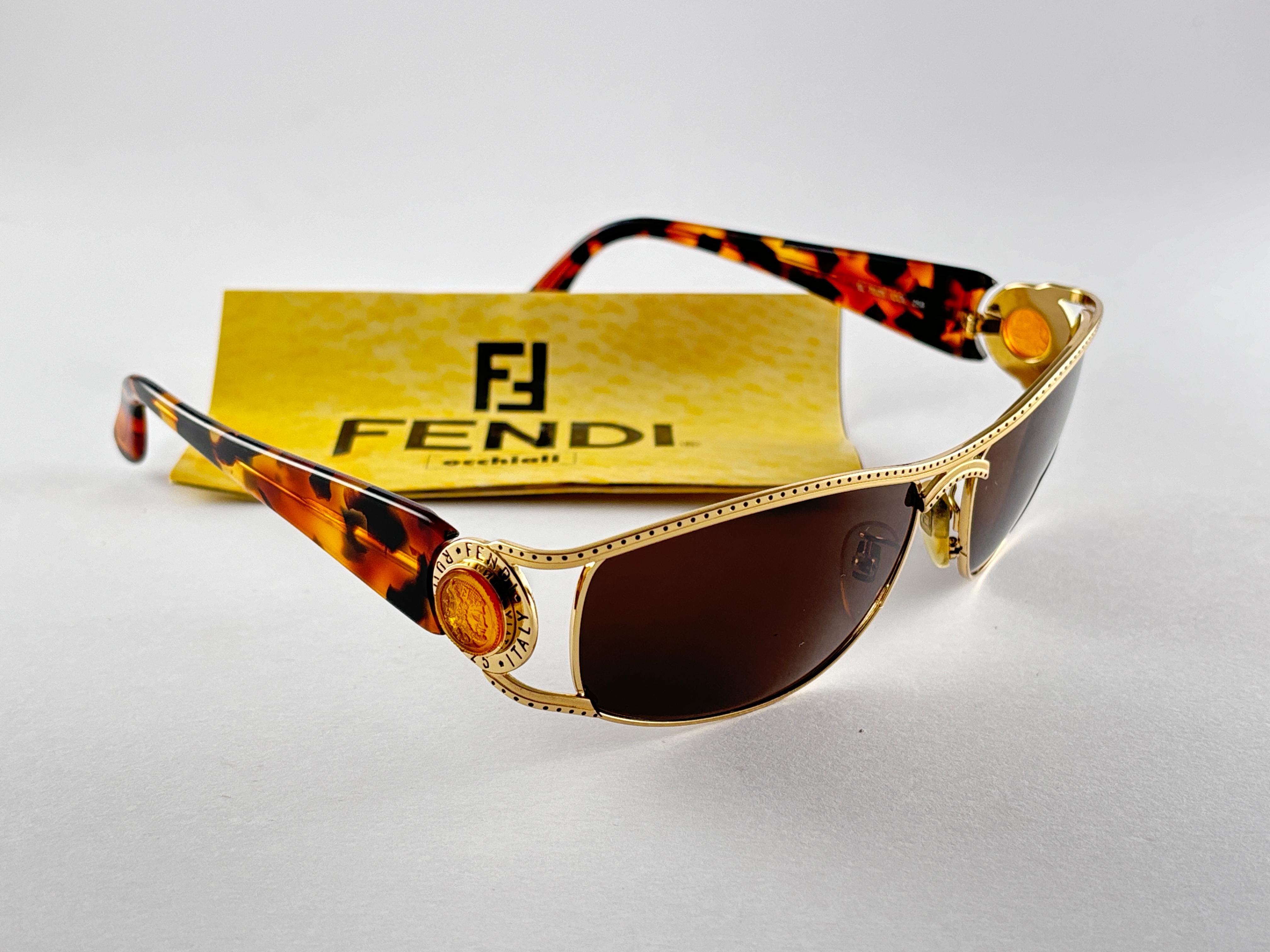 New Fendi gold & tortoise large frame with solid grey ( UV protection ) lenses.

Made in Italy.
 
Produced and design in 1990's.

New, never worn or displayed. this  item may show minor sign of wear due to storage.


FRONT : 14 CMS
LENS HEIGHT : 4.5