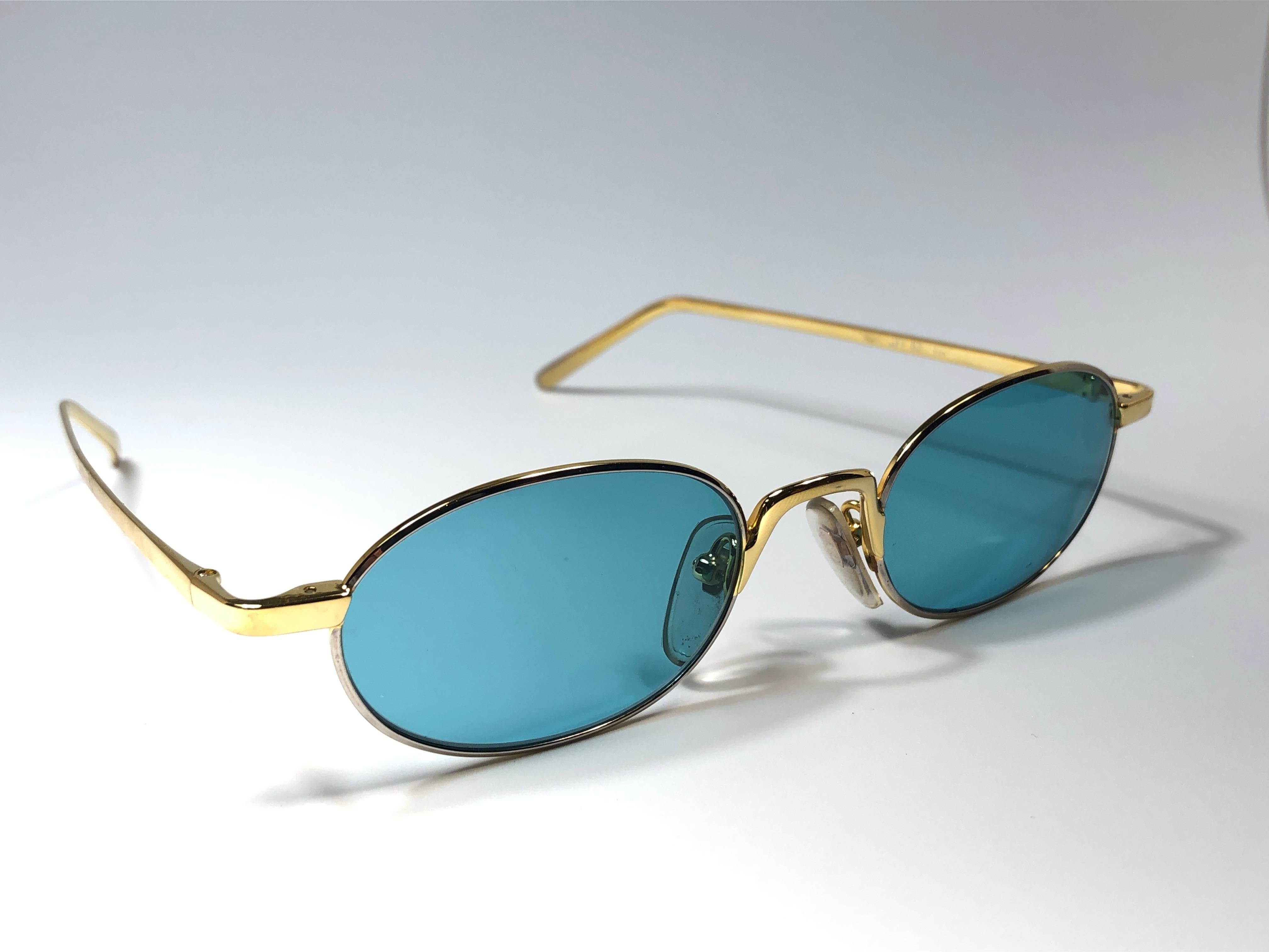 New vintage Gianfranco Ferre sunglasses.    

Oval gold frame holding a pair of spotless turquoise lenses.   

New, never worn or displayed. 

 Made in Italy.