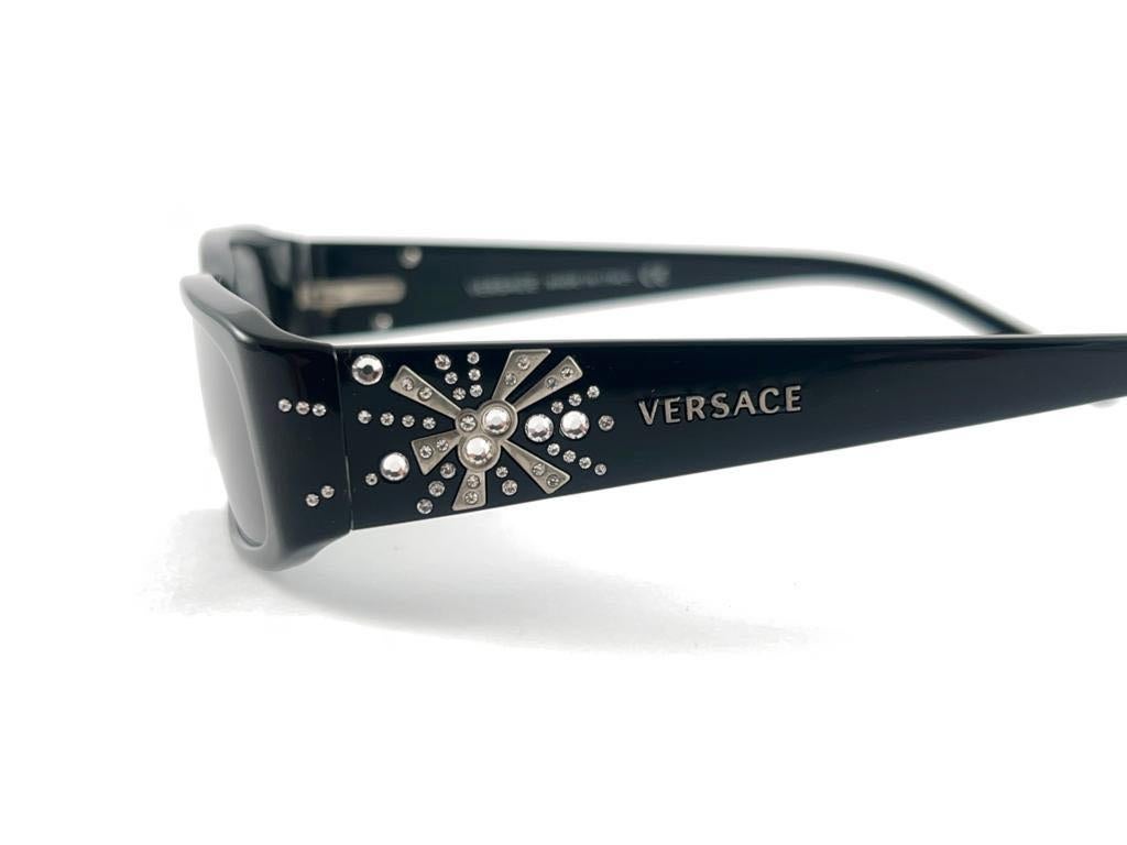 New Vintage Gianni Versace sleek Black With strass  Accents Frame With Medium Grey Lenses.
This pair could show minor sign of wear due to storage.

Made in italy.

Measurements
Front.                        12.5 cms
Lens Hight                 2.5