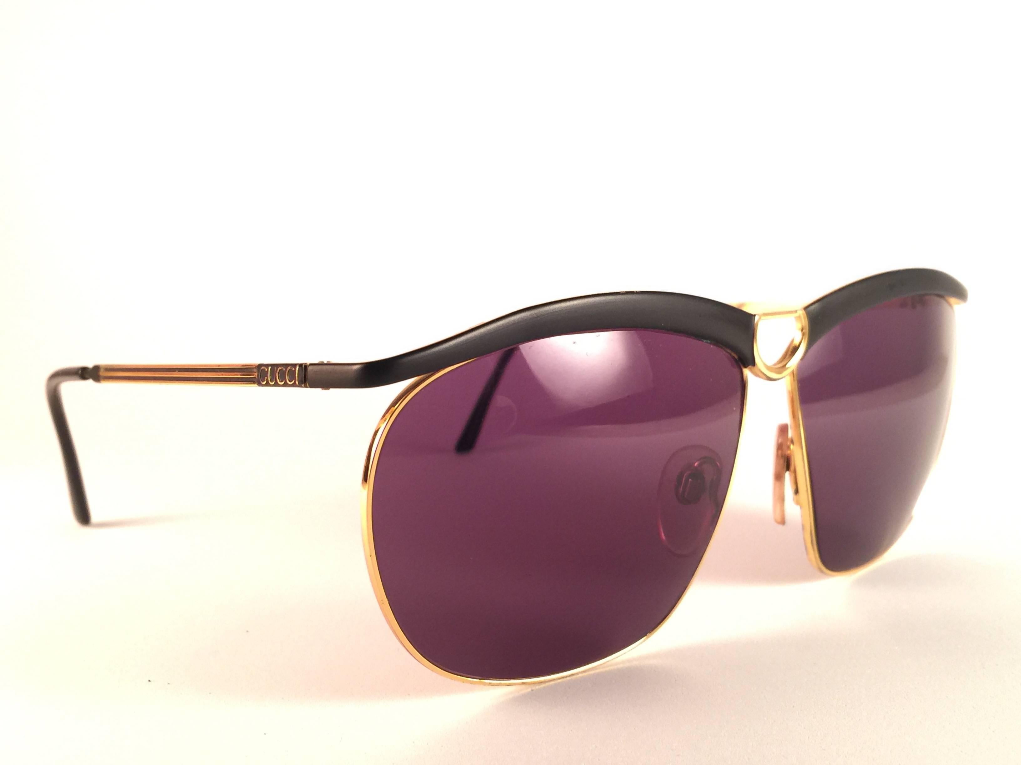 New Vintage Gucci Sunglasses in sleek black with gold details frame. Spotless purple lenses.  
New never worn or displayed. This item could show minor sign of wear due to nearly 30 years of storage. Made in Italy.
