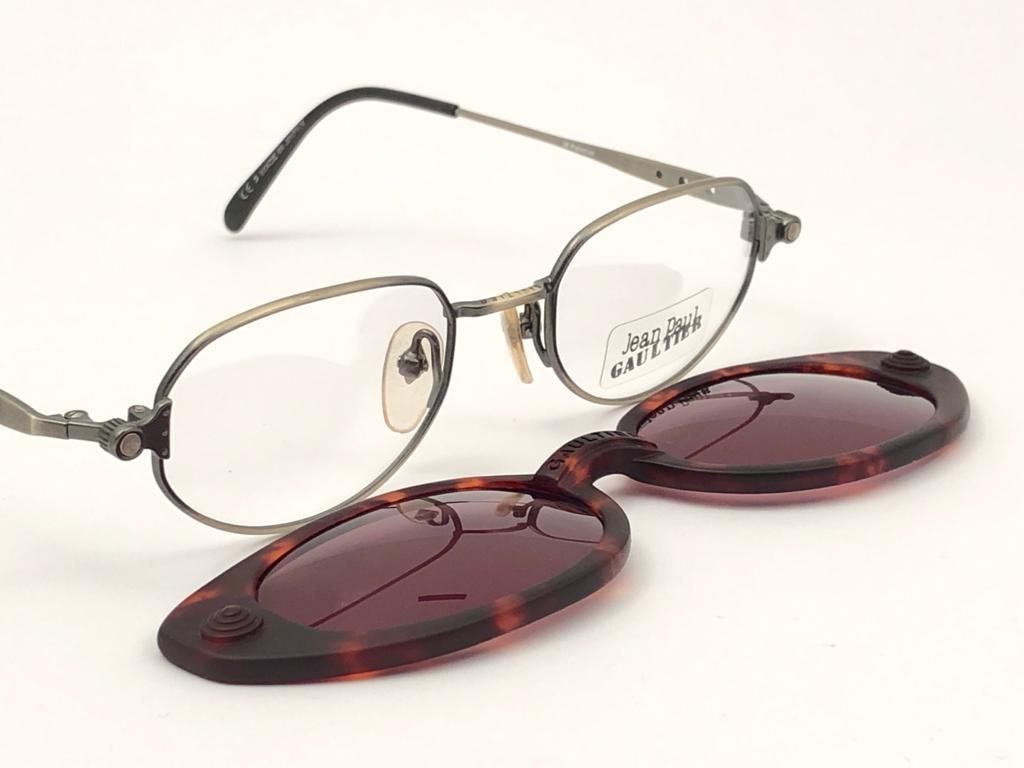 New Vintage Jean Paul Gaultier tortoise pattern magentic removable front.

Design and produced in the 1900's a timeless and iconic piece.
Ready for prescription lenses.
A true fashion statement.

FRONT : 13.5 CMS

LENS HEIGHT : 3.2 CMS

LENS WIDTH :