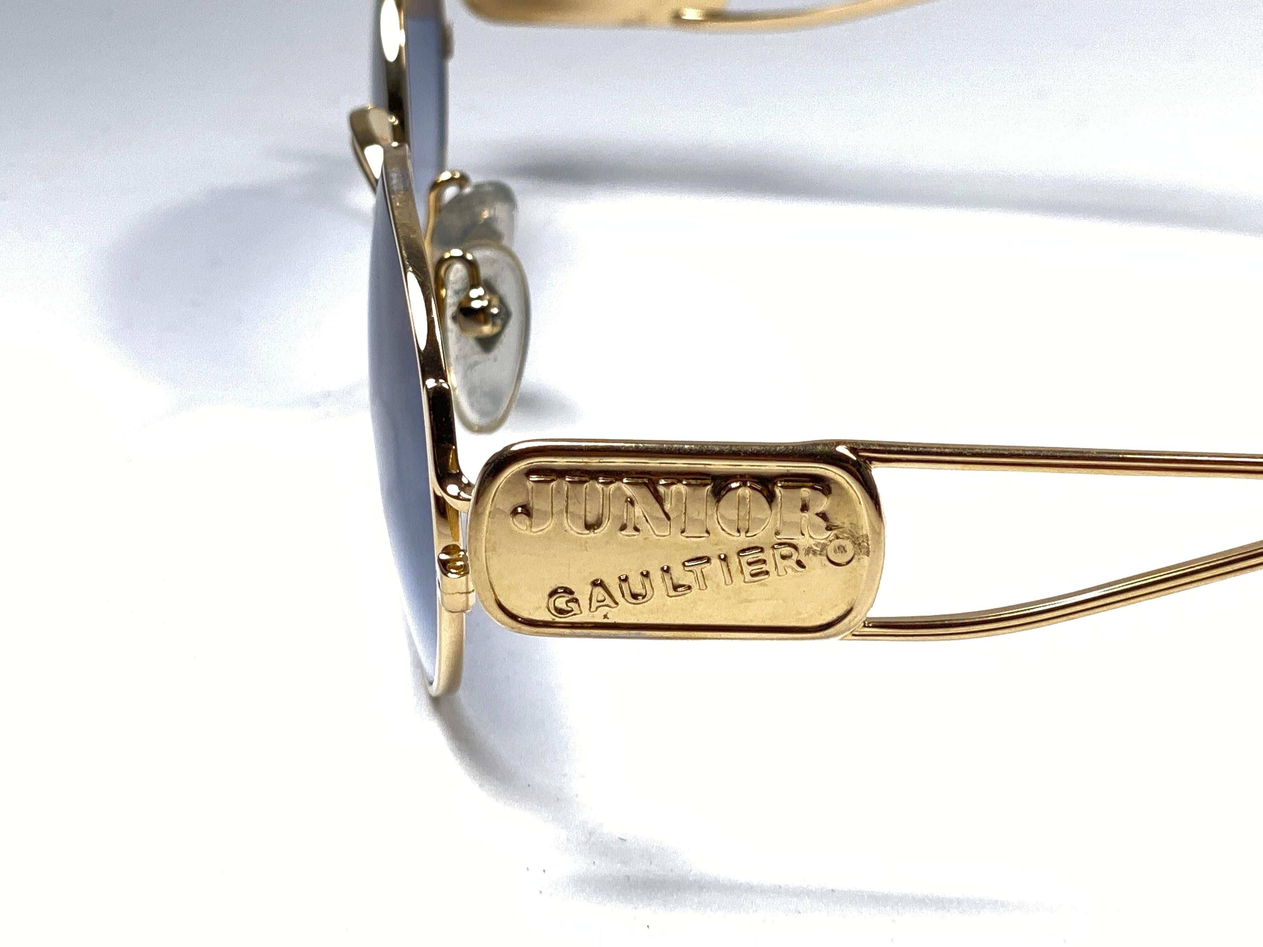 New Vintage Jean Paul Gaultier Junior medium frame in gold.

Design and produced in the 1900's a timeless and iconic piece.
Spotless blue gradient lenses.
A true fashion statement.

FRONT : 1.5 CMS

LENS HEIGHT : 4 CMS

LENS WIDTH : 5 CMS

TEMPLES :