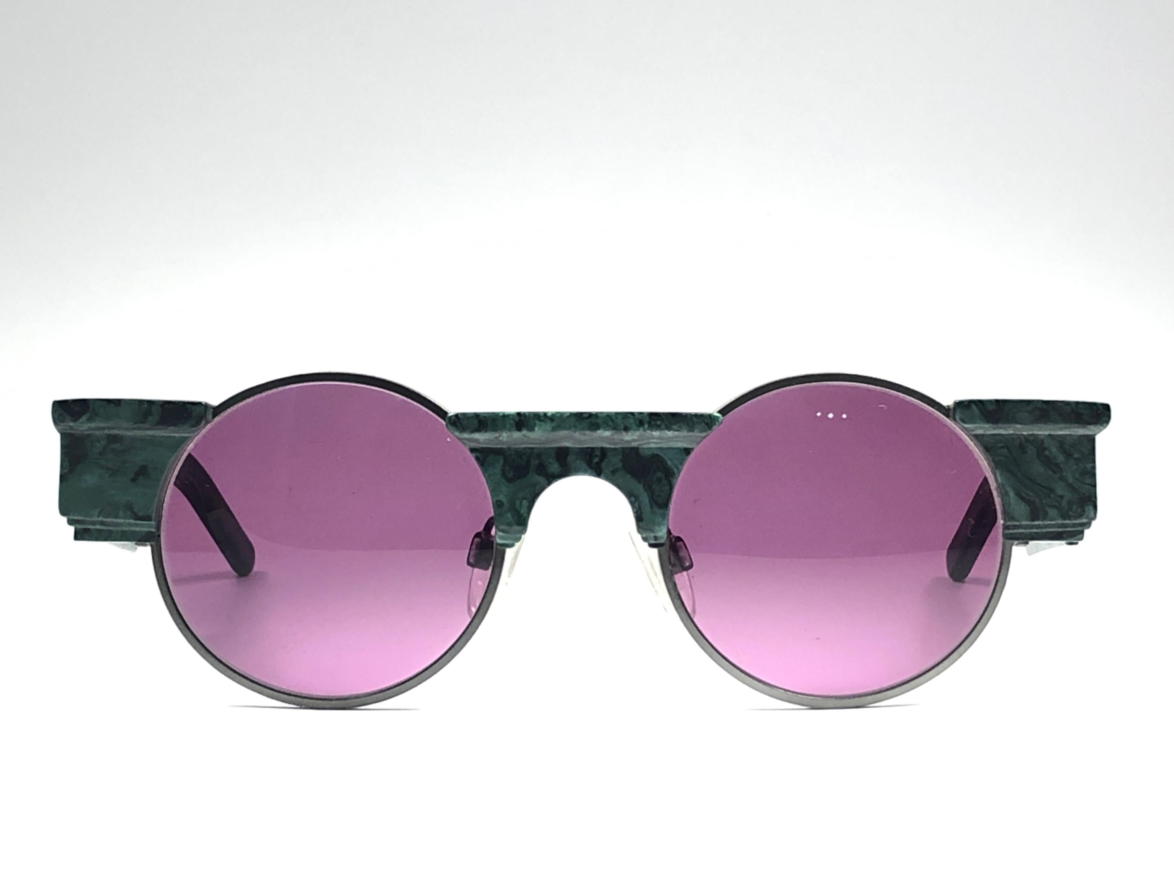 
Striking pair of vintage Karl Lagerfeld Round dark green marbled sunglasses sporting a pair of purple lenses. Superb design emulating ancient greek architecture. 

Front :  14 cms
Lens Height : 4.5 cms
Lens Width : 5 cms.
 
Although it has never