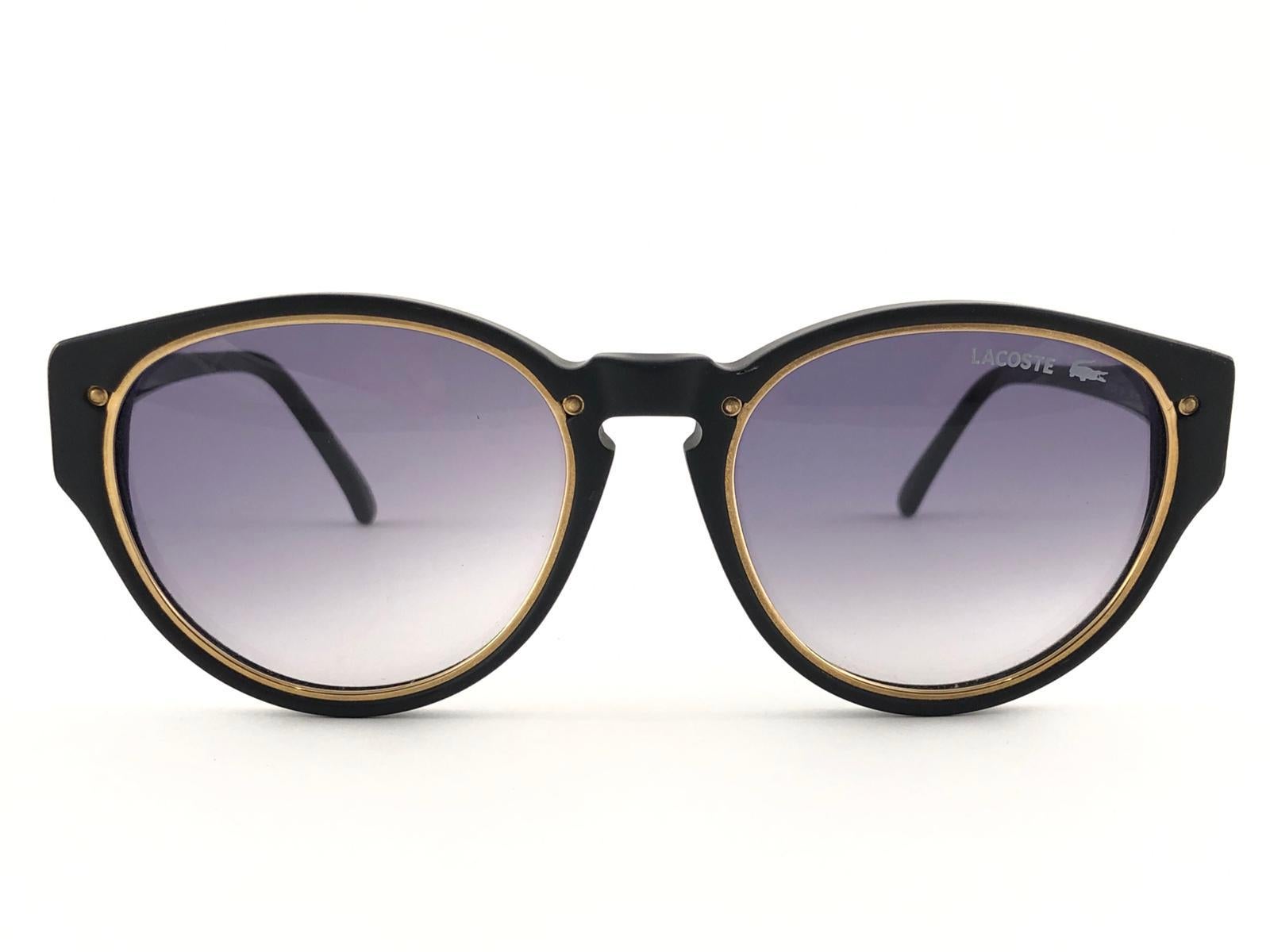 New Vintage Lacoste matte black with gold accents frame holding a pair of medium grey lenses. 
This pair may have minor sign of wear on the lens due to storage. 
New, never worn or displayed. 
Design and produced in France.


MEASUREMENTS

FRONT :  