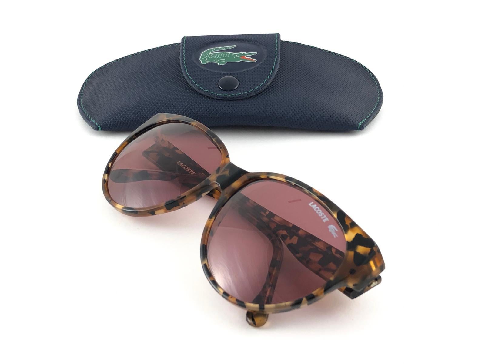 New Vintage Lacoste tortoise frame holding a pair of mauve lenses. 
This pair may have minor sign of wear on the lens due to storage. 
New, never worn or displayed. 
Design and produced in France.



MEASUREMENTS

FRONT :            14   CMS
LENS