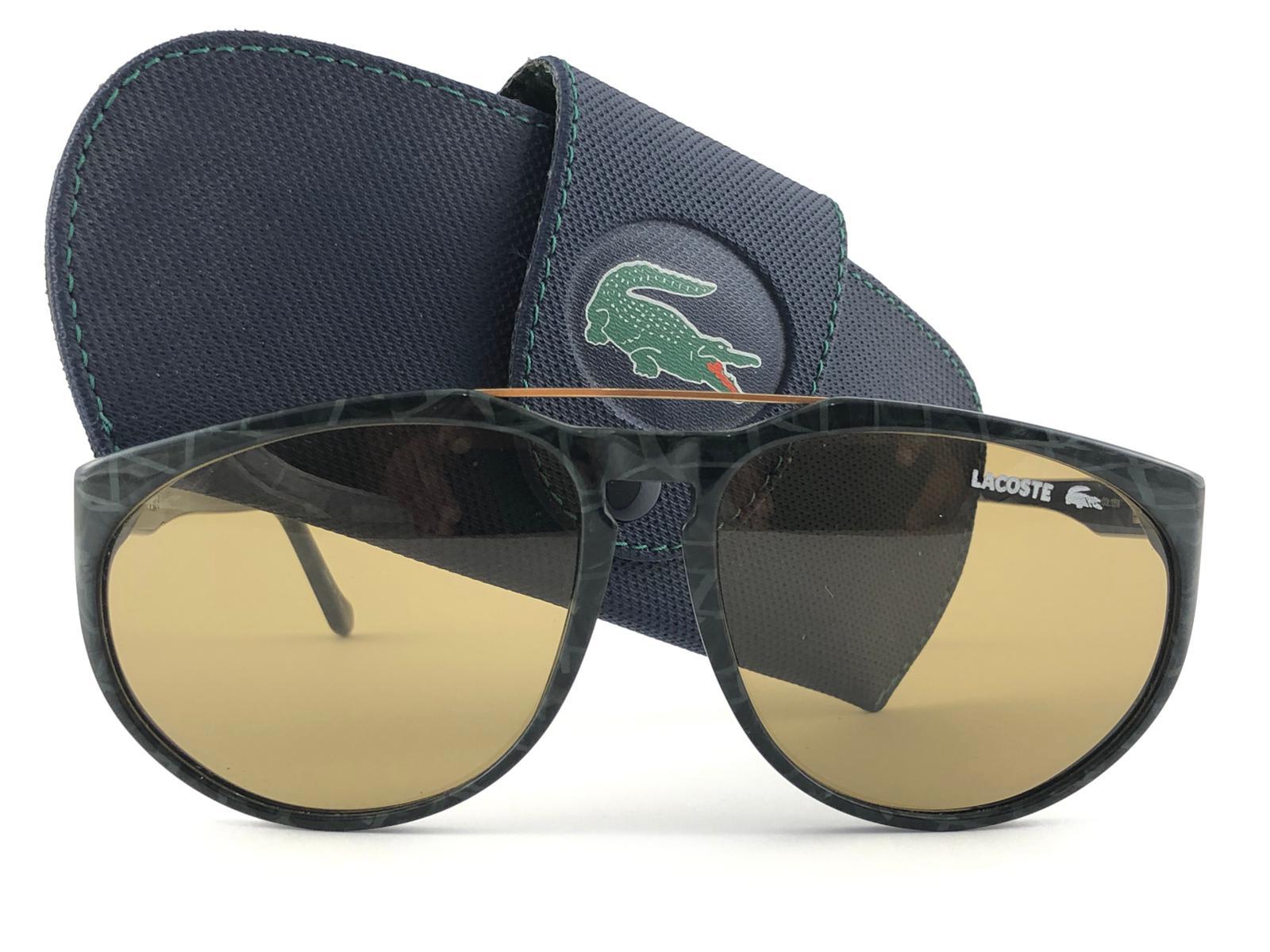 New Vintage By Lacoste marmoriert grün mit goldenen Akzenten Rahmen hält ein Paar Medium braune Gläser. 
Dieses Paar kann aufgrund der Lagerung geringfügige Abnutzungserscheinungen auf dem Glas aufweisen. 
Neu, nie getragen oder ausgestellt.