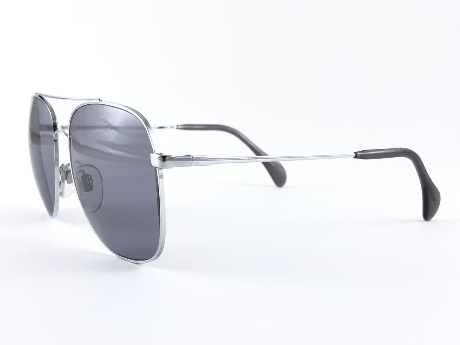 New Vintage Collector Item Menrad Silver Aviator frame Sunglasses holding a pair of medium grey lenses.  

Fabriqué en Allemagne dans les années 1970.



Front :                    14 cm 

Hauteur de l'objectif :       5.2 cm 

Largeur de l'objectif