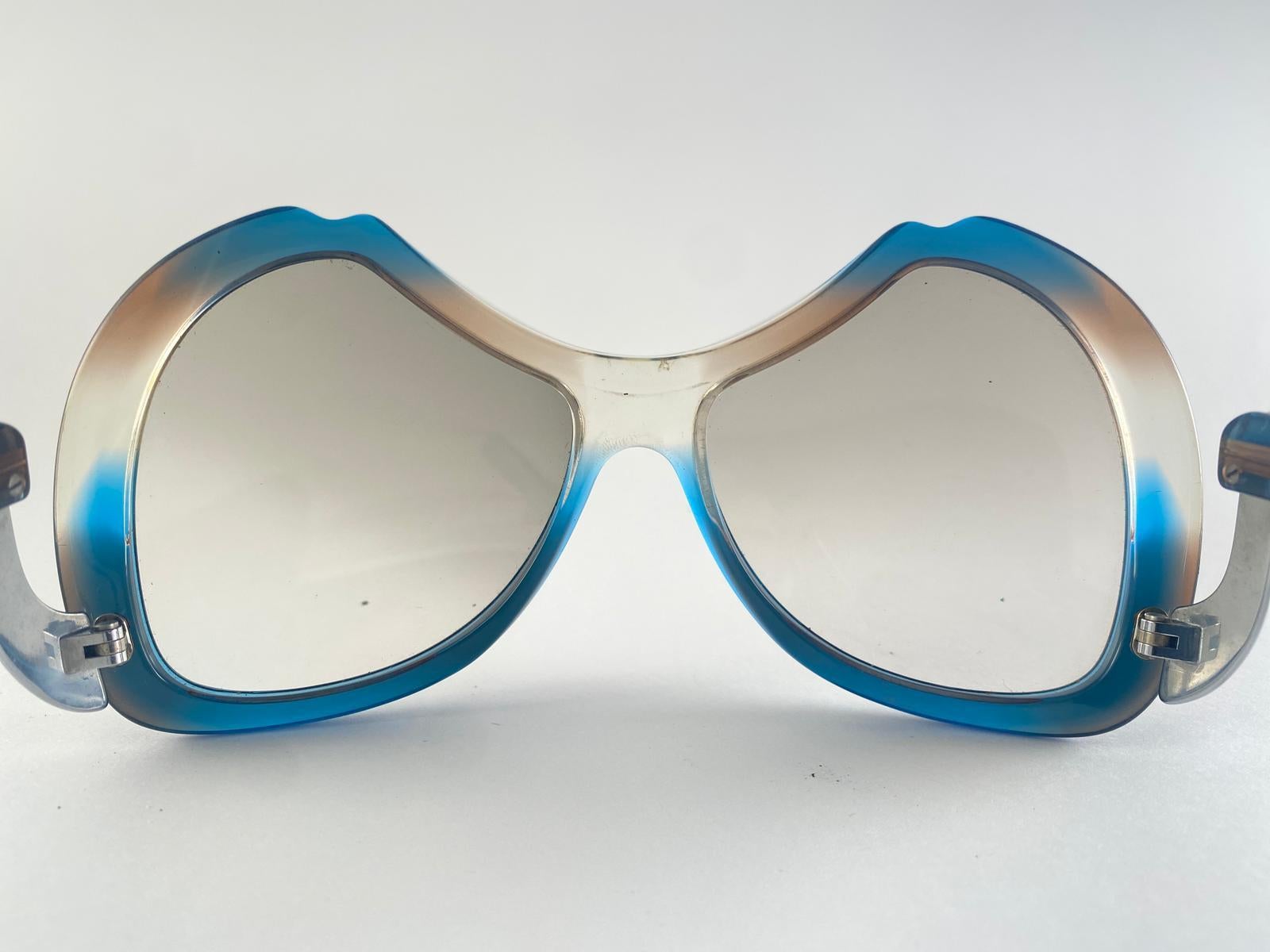 New Vintage Collector Item Menrad Clear Multicolour And Silver Sunglasses Frame Holding A Spotless Pair Of Light Gradient Lenses.  

Hergestellt in Deutschland in den 1970er Jahren.

Vorderseite : 15 Zentimeter
Linse Höhe : 6 cm
Linse Breite : 6