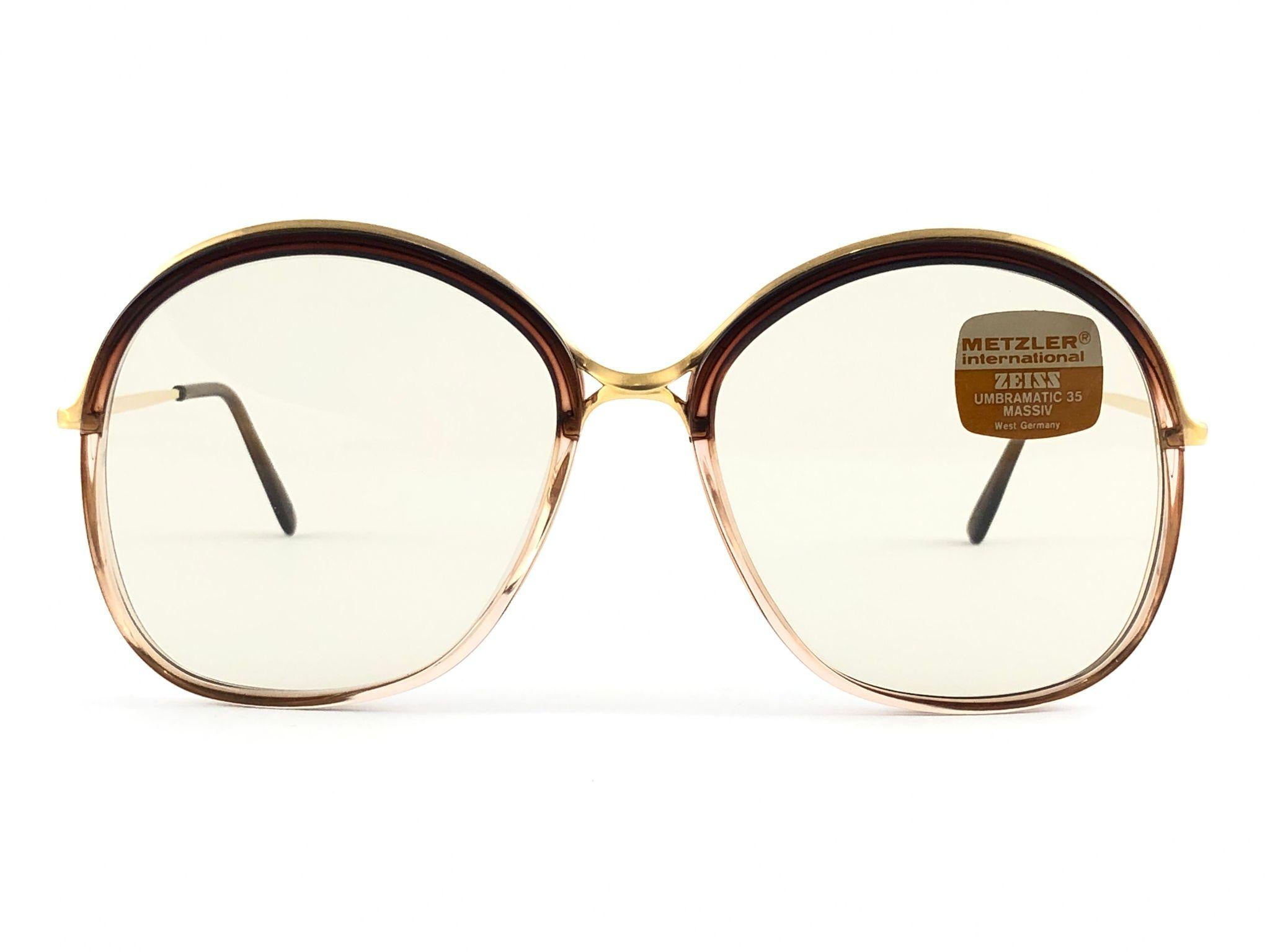 Occhiali da sole Metzler Zeiss 1830 Umbramatic 35 . Prodotto in Germania Ovest negli anni '80. 

Montatura oversize in metallo e acetato traslucido borgogna con un paio di Umbramatic35 senza macchia.  lenti.

MISURE:

Anteriore :                    