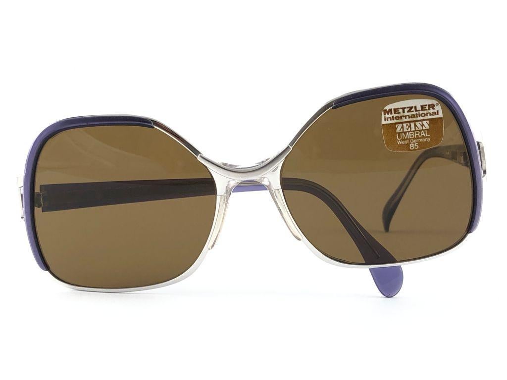 Sunglasses Metzler Zeiss 870 Umbramatic 85 oversized . Made in West Germany 1980's. 

Oversized Metallic & Acetate purple and silver frame holding a spotless pair of medium brown lenses.

MEASUREMENTS:

Front :                      14 cms
Lens