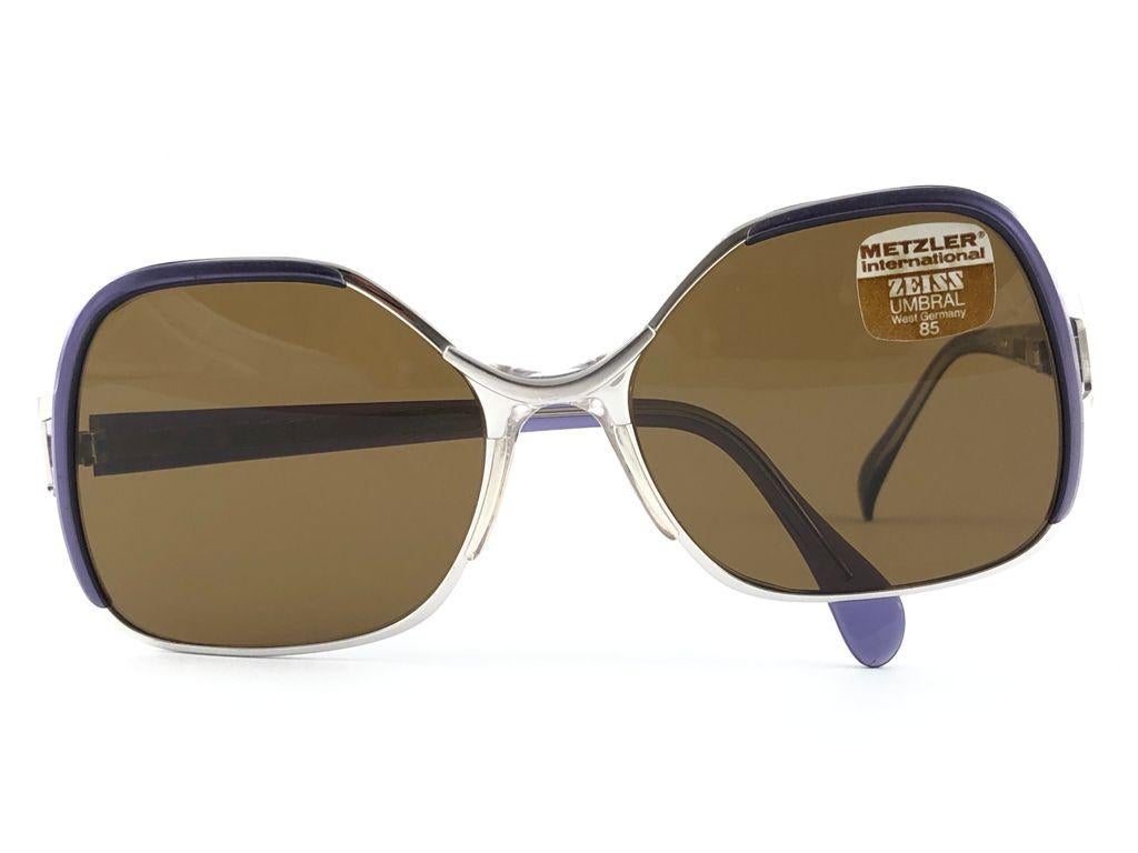 Sonnenbrille Metzler Zeiss 870 Umbramatic 85 übergroß . Hergestellt in Westdeutschland in den 1980er Jahren. 

Übergroßer Metallic- und Acetat-Rahmen in Lila und Silber mit einem makellosen Paar mittelbrauner Gläser.

MASSNAHMEN:

Vorderseite :     