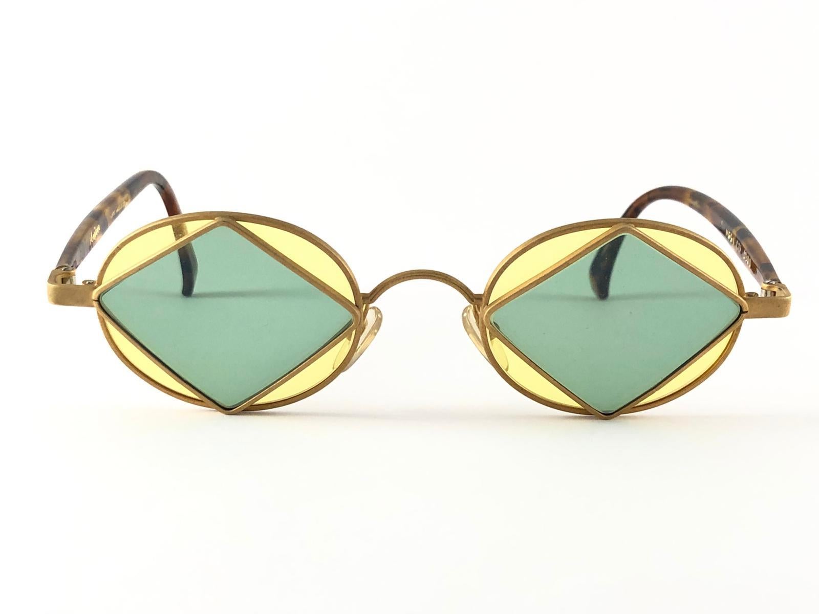 New Vintage Montana frame in matte gold with inner triangles with green and yellow lenses.

This item is in unworn condition. Please consider that this item is nearly 30 years old so it could show minor sign of wear due to storage.  

Made in