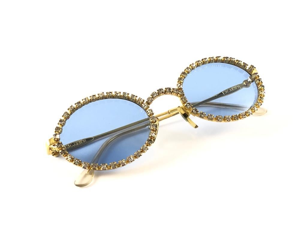New Vintage Moschino with rhinestones accents frame. Spotless turquoise lenses.

Made in Italy.
 
Produced and design in 1990's.

This item may show minor sign of wear due to storage.

FRONT : 13.5 CMS
LENS HEIGHT : 4 CMS 
LENS WIDTH : 5 CMS
