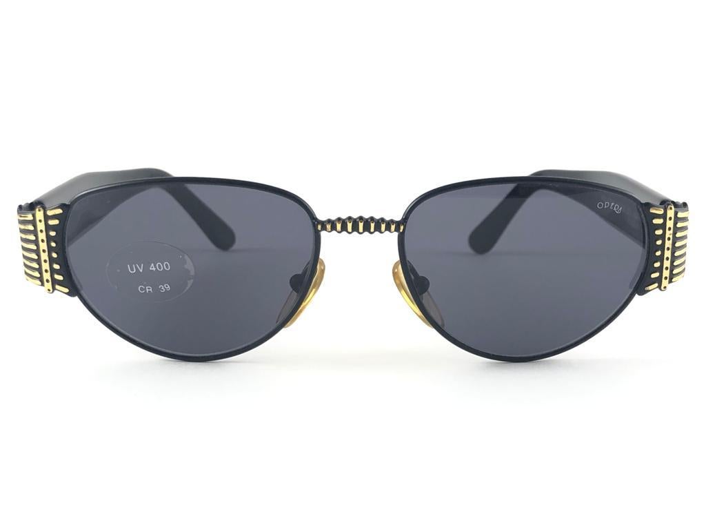 New Opera black and gold oval frame with dark grey ( UV protection ) lenses.

Made in Italy.
 
Produced and design in 1990's.

New, never worn or displayed. this  item may show minor sign of wear due to storage.

FRONT                   14 CMS
LENS