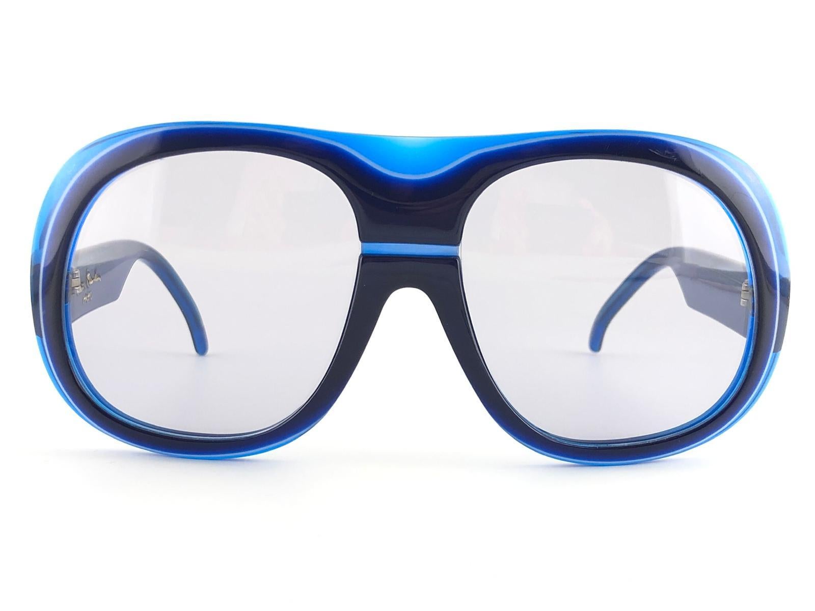 
New Vintage Pierre Cardin vibrant blue frame with medium grey lenses. 

This pair has slight wear on them due to 50 years of storage.  

New, never worn or display. A must have!

MEASUREMENTS :


FRONT : 15 CMS

LENS HEIGHT : 6.6 CMS

LENS WIDTH :