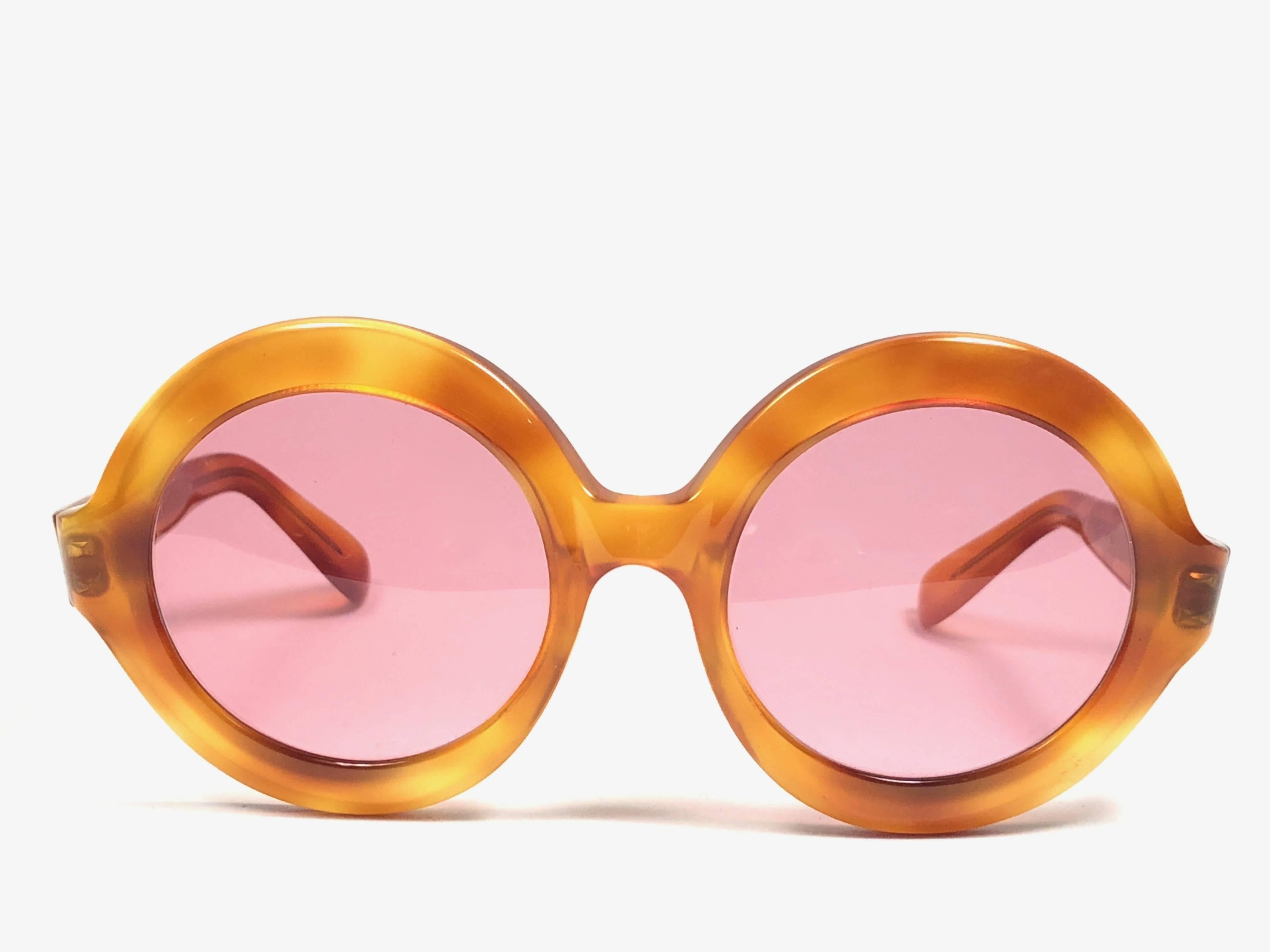 Vintage new Pierre Cardin medium round honey tortoise frame with rose lenses. 

New, never used or displayed this pair of vintage Pierre Cardin is a rare and sought after piece not to miss out!