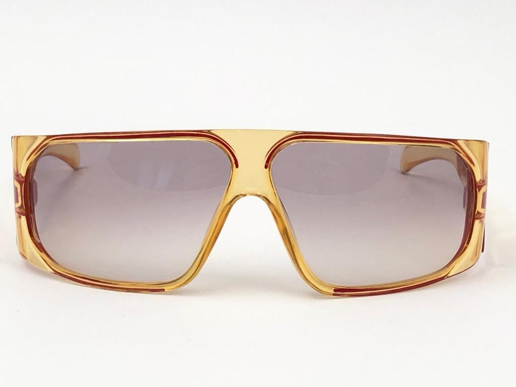 New Vintage Playboy Optyl translucent yellow frame sporting spotless light gradient lenses. 

Made in Germany.
 
Produced and design in 1970's.


FRONT : 15 CMS

LENS HEIGHT : 3.6 CMS

LENS WIDTH : 6.5 CMS

TEMPLES : 11 CMS

New, never worn or