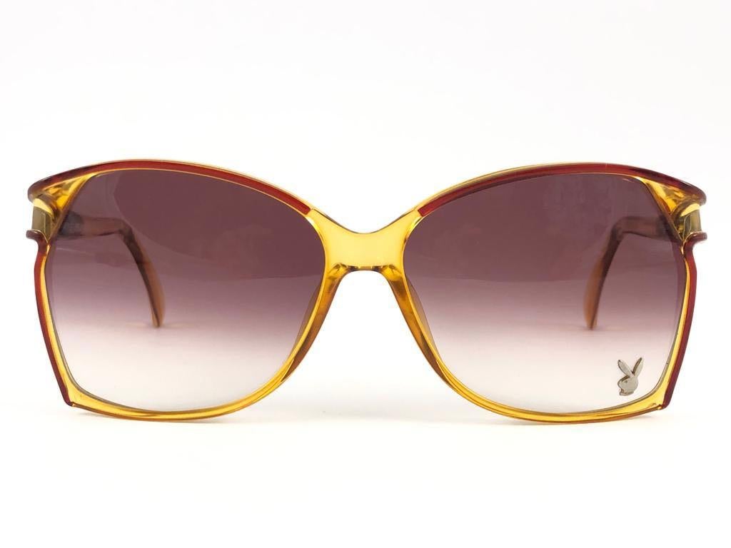 New Vintage Playboy Optyl translucent yellow frame sporting spotless mauve gradient lenses. 

Made in Germany.
 
Produced and design in 1970's.


FRONT : 15 CMS

LENS HEIGHT : 5.5 CMS

LENS WIDTH : 6 CMS

TEMPLES : 12 CMS

New, never worn or
