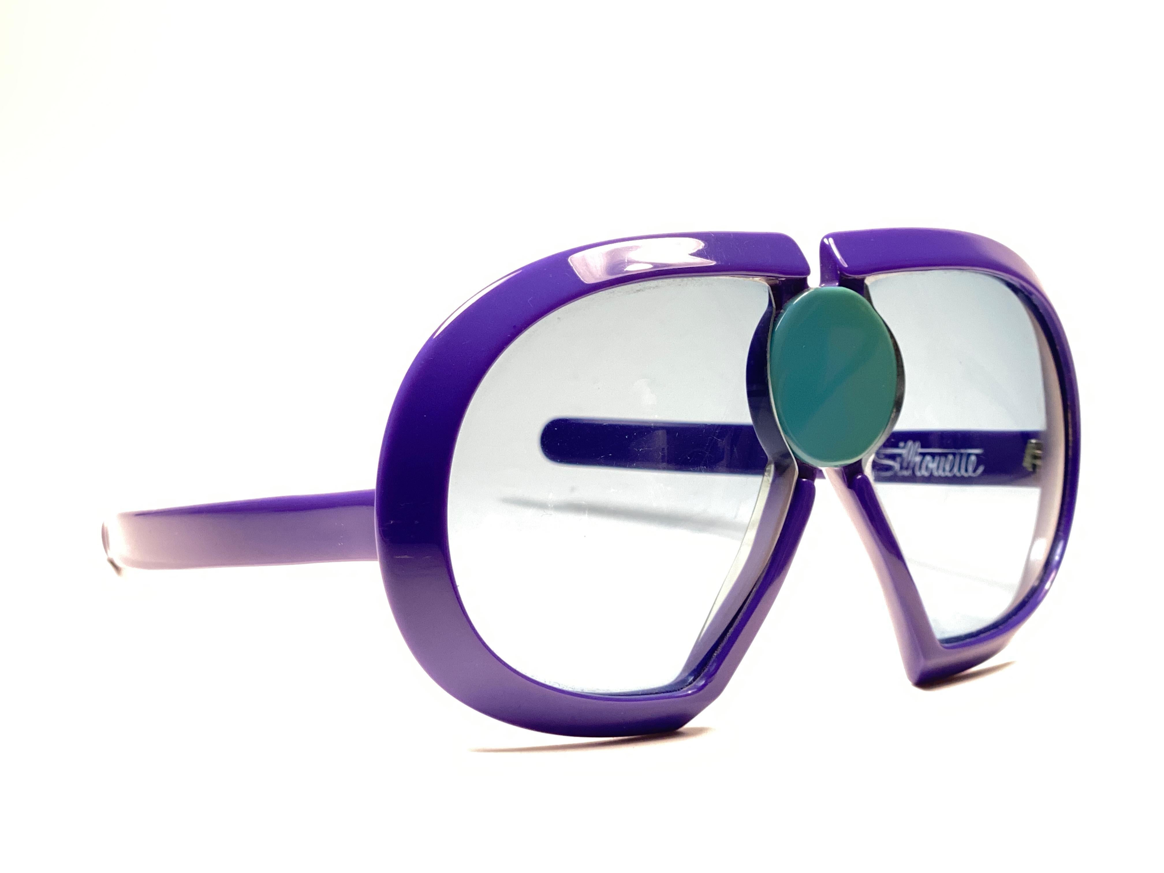 New Vintage Collector Item Silhouette Futura 571 purple thick frame with blue ornament holding a spotless pair of light blue lenses.   

Designed by Dora Demmel in 1973, this rare piece is the epitome of avant garde & futuristic eye wear