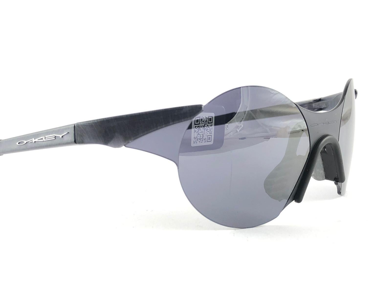 New Vintage are Oakley Sunglasses. Wrap black & grey sports frame with grey mirror lenses.
New never worn or displayed. This item might show minor sign of wear due to storage.

Made in Germany.

FRONT 14
LENS HEIGHT 4.8
LENS WIDTH 4.8
TEMPLES 13