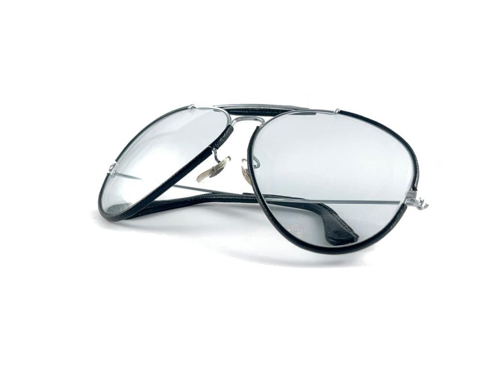 
Nuovo Ray Ban Outdoorsman vintage in pelle nera da 62 mm con lenti grigie intercambiabili con logo Ray Ban. 

B&L inciso sulle lenti.

Viene fornito con la sua custodia originale Ray Ban B&L. Si prega di notare che questo articolo può presentare